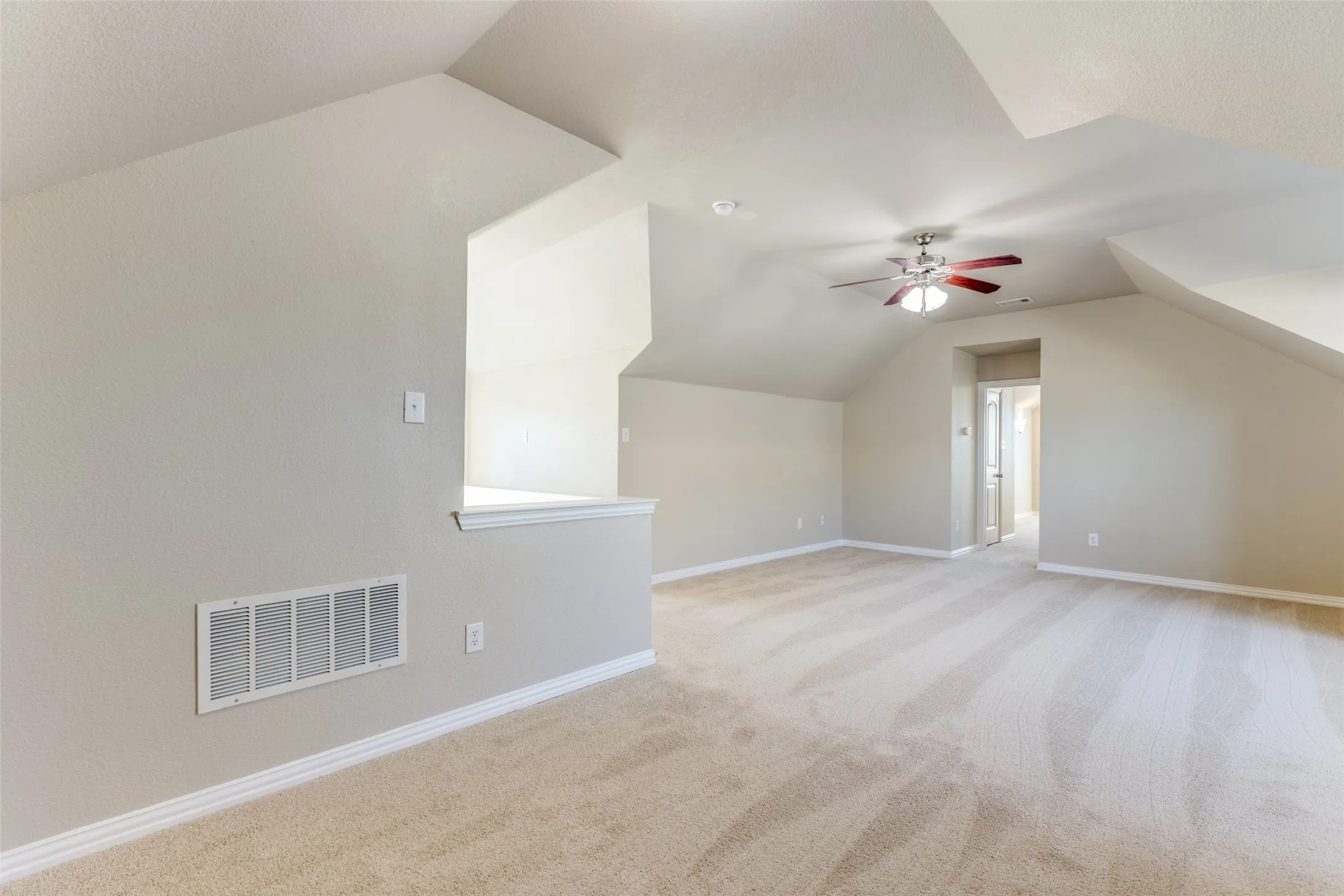Bonus room with light carpet, ceiling fan, and vaulted ceiling