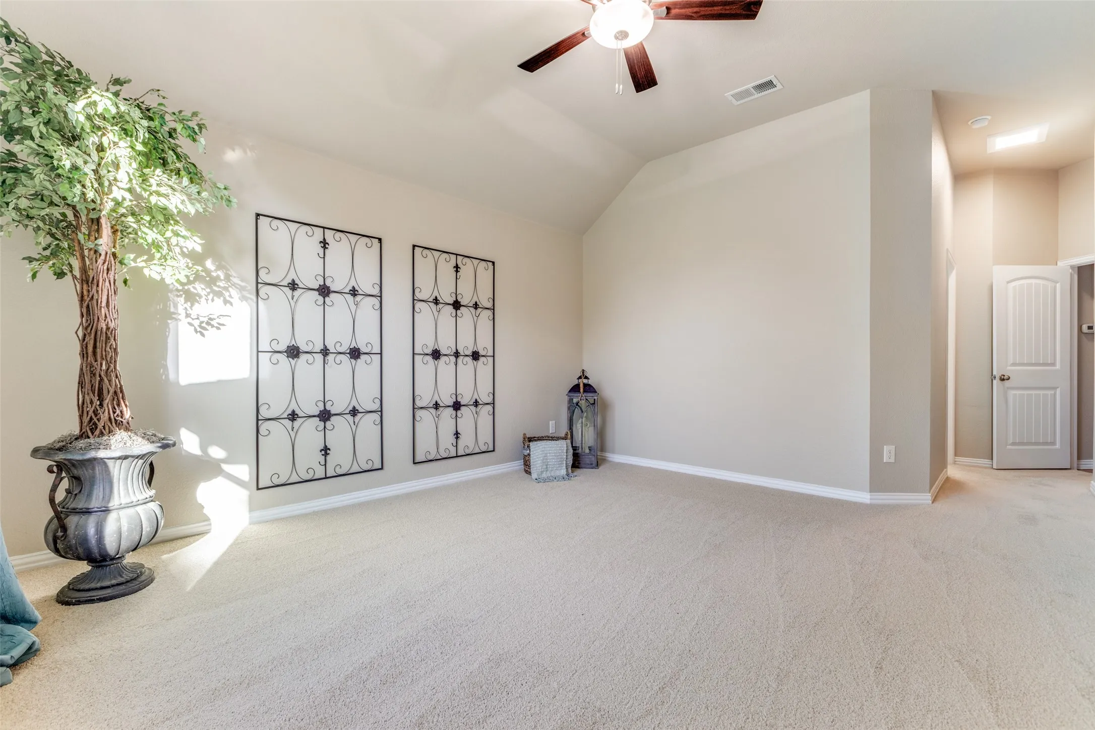Master suite with light carpet, ceiling fan, and vaulted ceiling