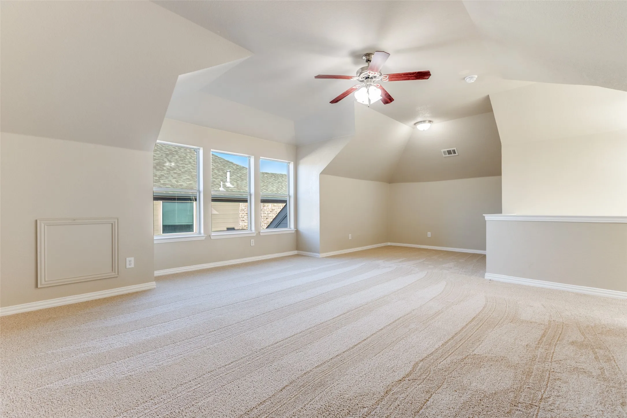 Additional living space featuring a ceiling fan, light carpet, and lofted ceiling