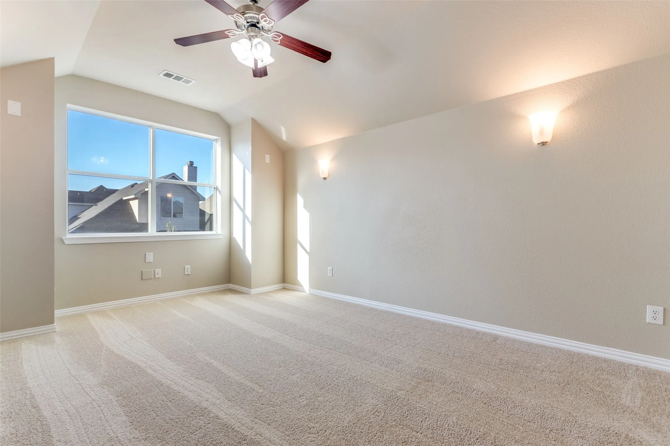 Carpeted room featuring a ceiling fan and vaulted ceiling