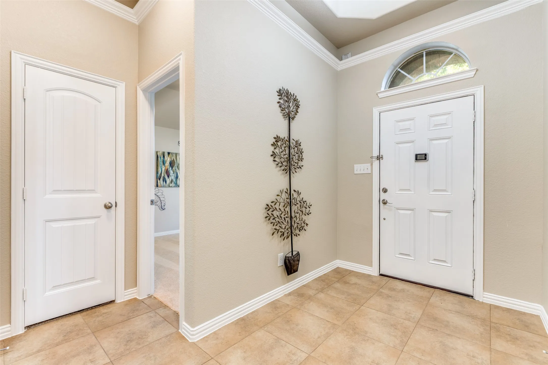 Entrance foyer featuring crown molding and light tile patterned floors