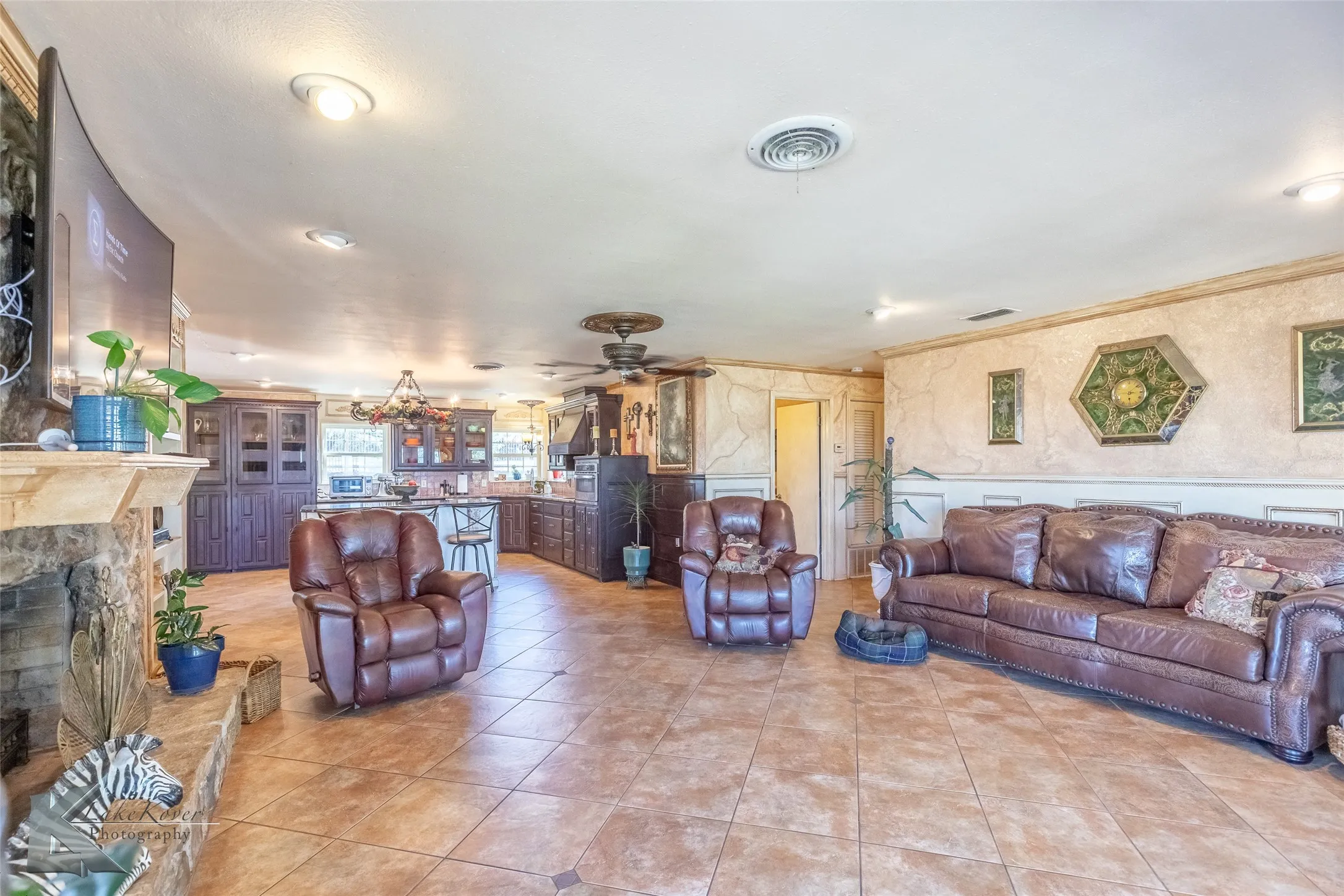 Living room with a fireplace, light tile patterned flooring, ornamental molding, and a ceiling fan