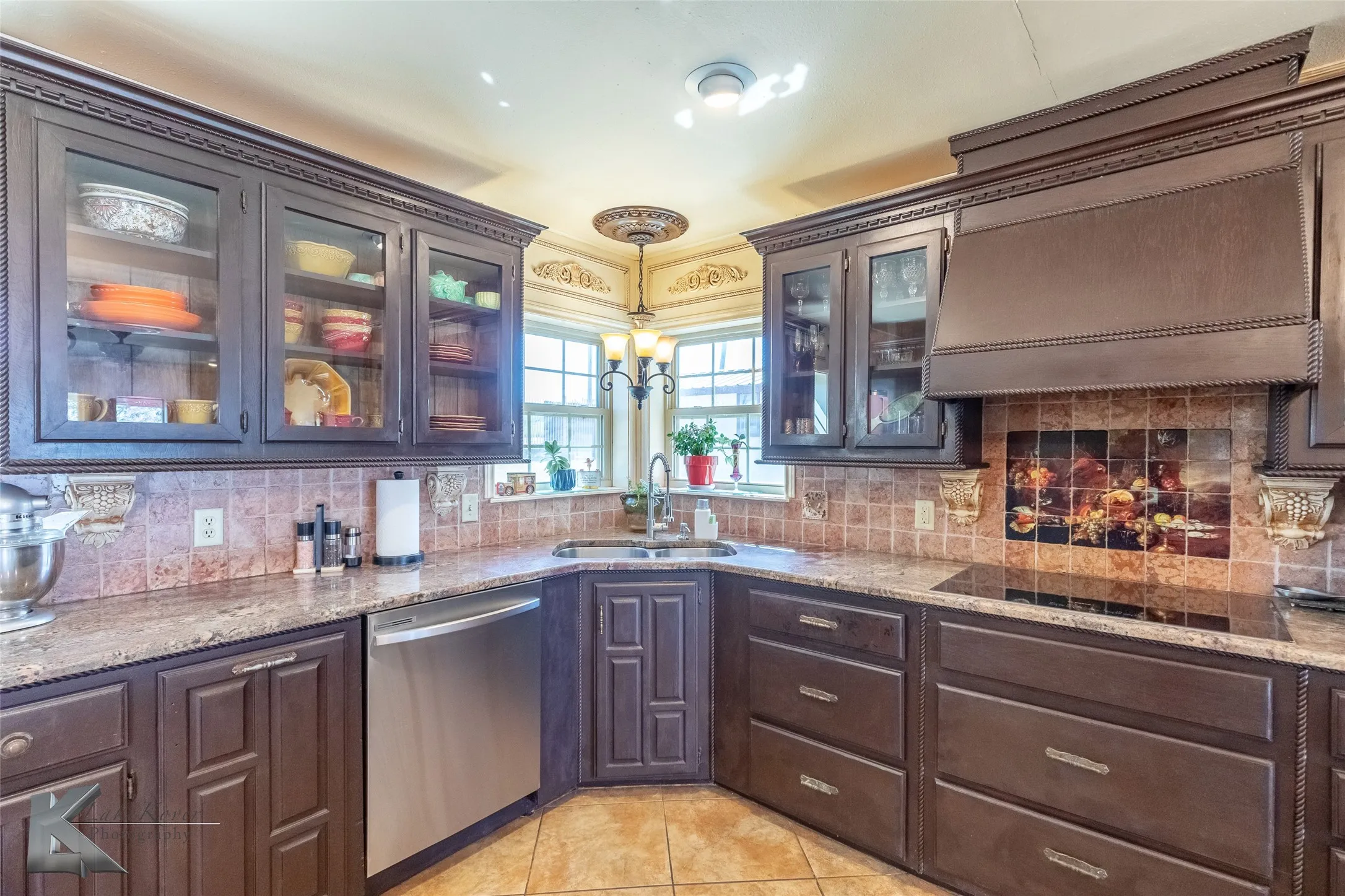 Bar area featuring dishwasher, tasteful backsplash, dark brown cabinets, light stone countertops, and glass insert cabinets