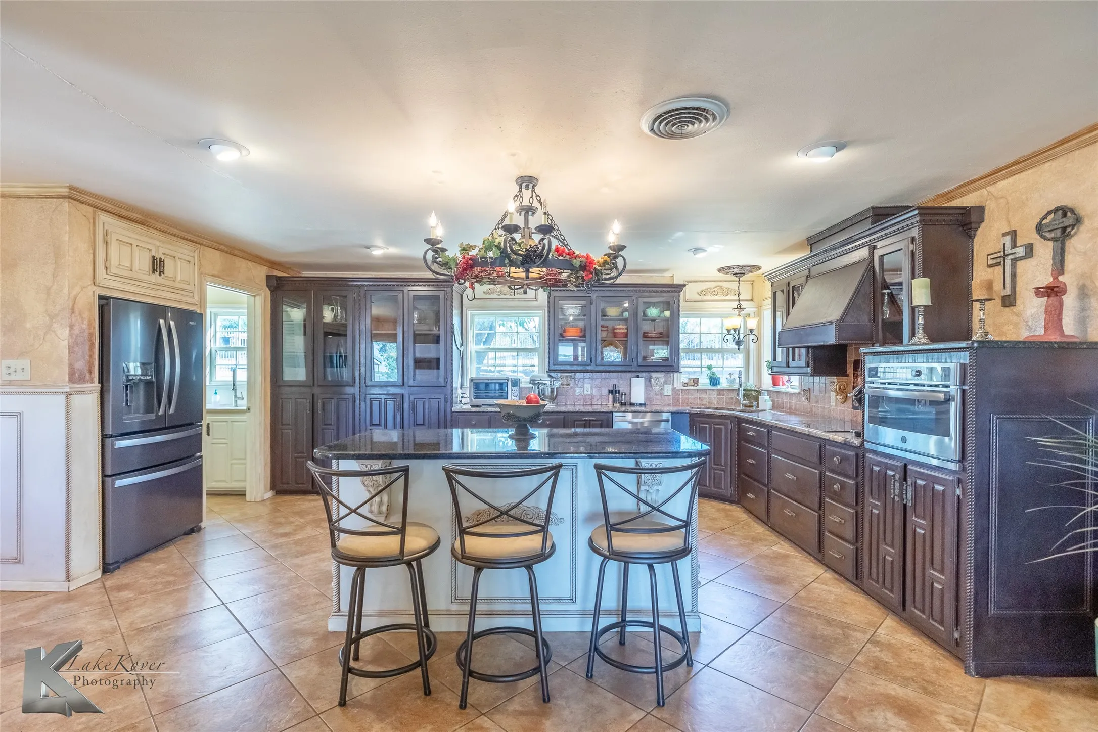 Kitchen featuring glass insert cabinets, stainless steel appliances, plenty of natural light, a kitchen island, and ornamental molding