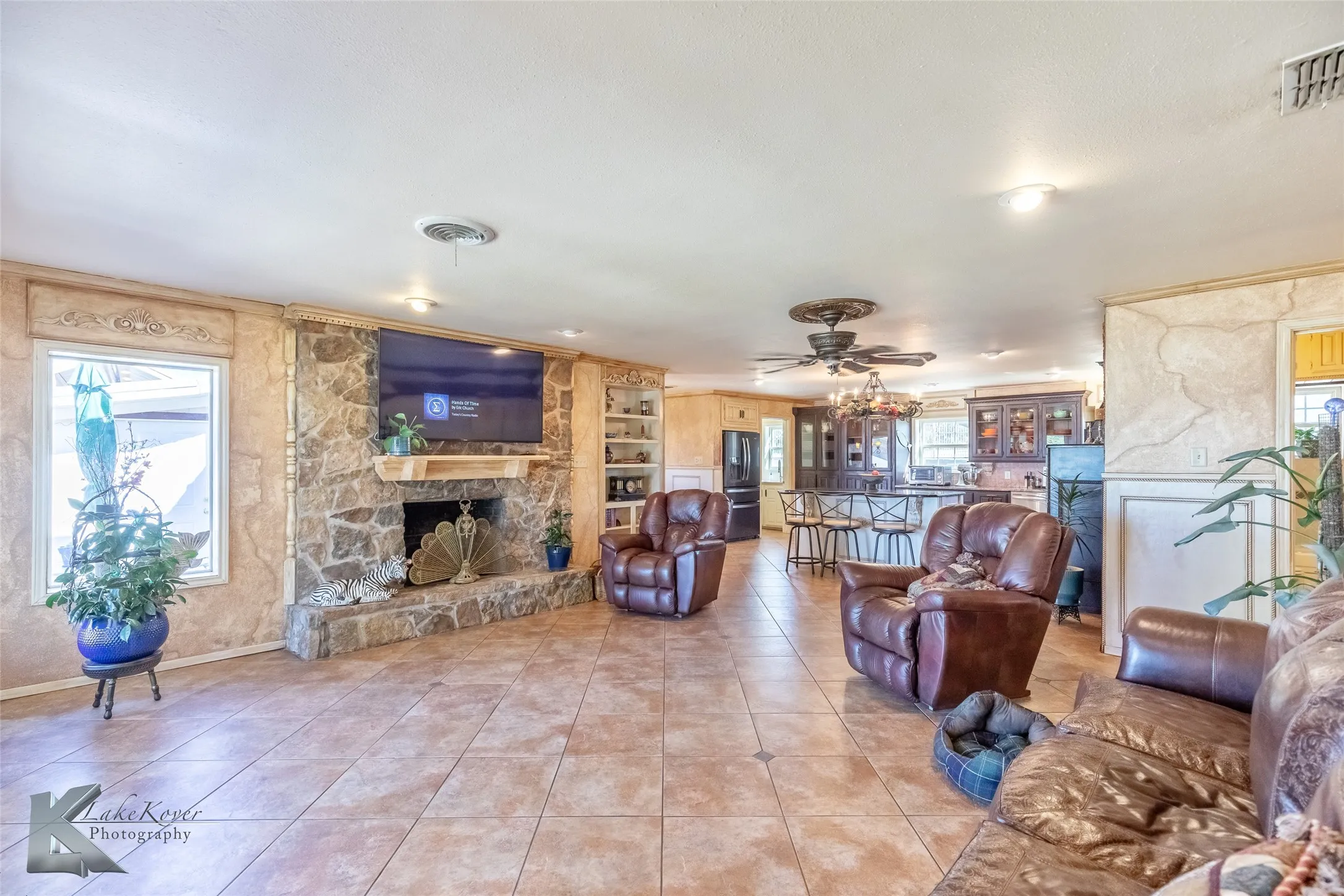 Tiled living area featuring a fireplace and a ceiling fan