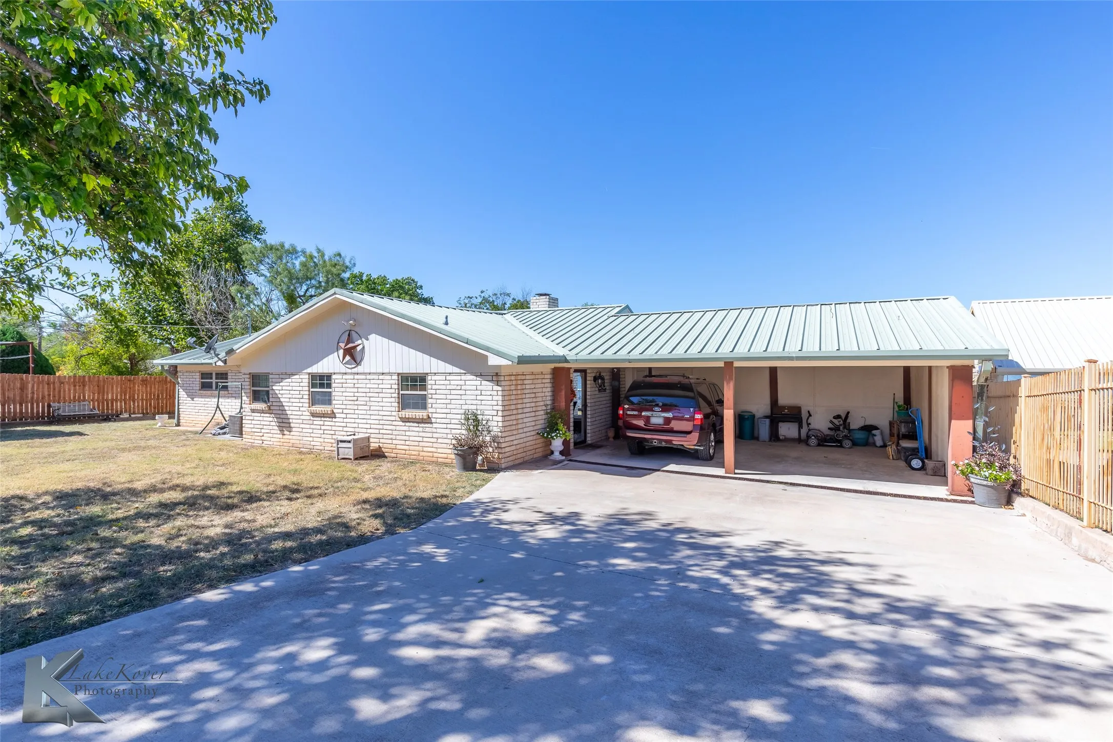 View of front of home featuring brick siding, concrete driveway, an attached carport, and a metal roof