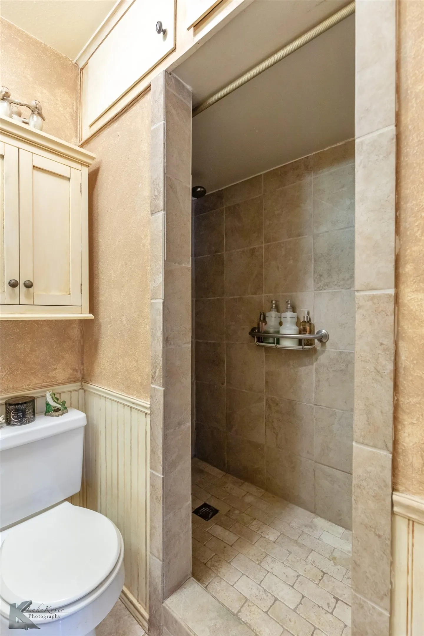 Full bath featuring a shower stall and wainscoting