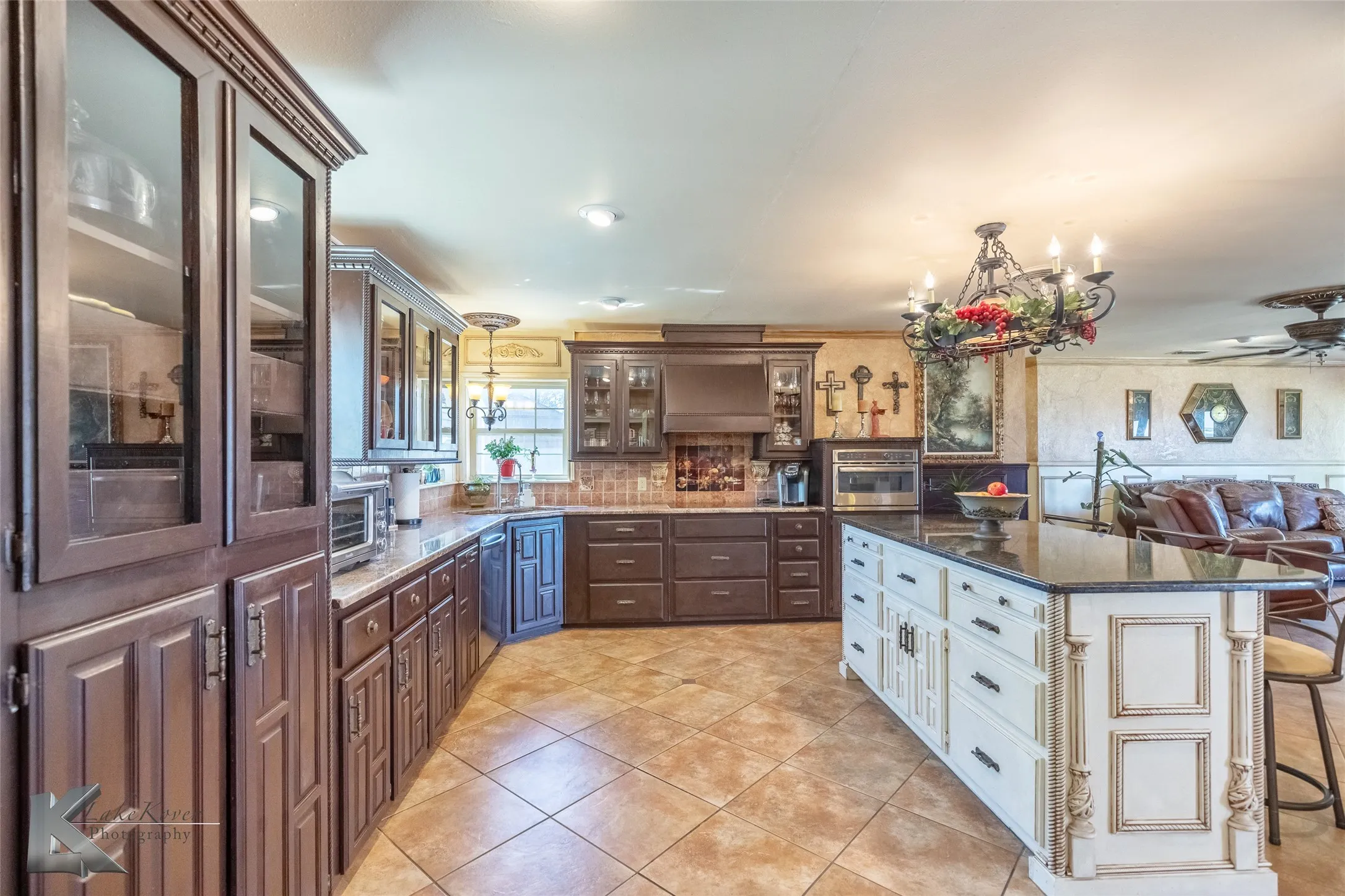 Kitchen with a chandelier, white cabinetry, granite countertops, a kitchen bar, and light tile patterned floors