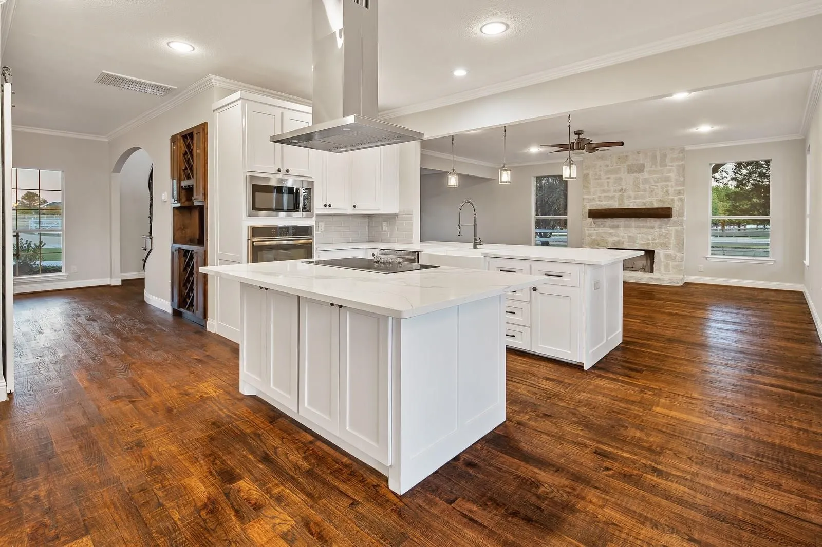 Kitchen with decorative light fixtures, white cabinetry, ornamental molding, island range hood, and a kitchen island