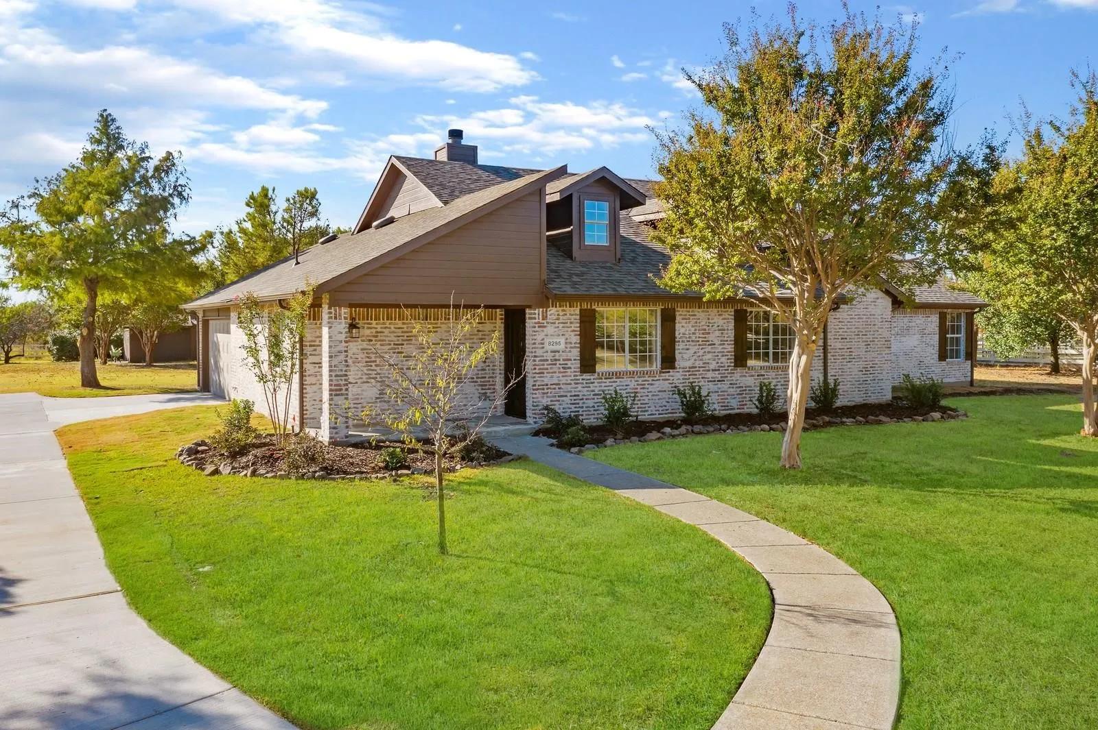 View of front facade featuring a front lawn, a chimney, brick siding, and concrete driveway