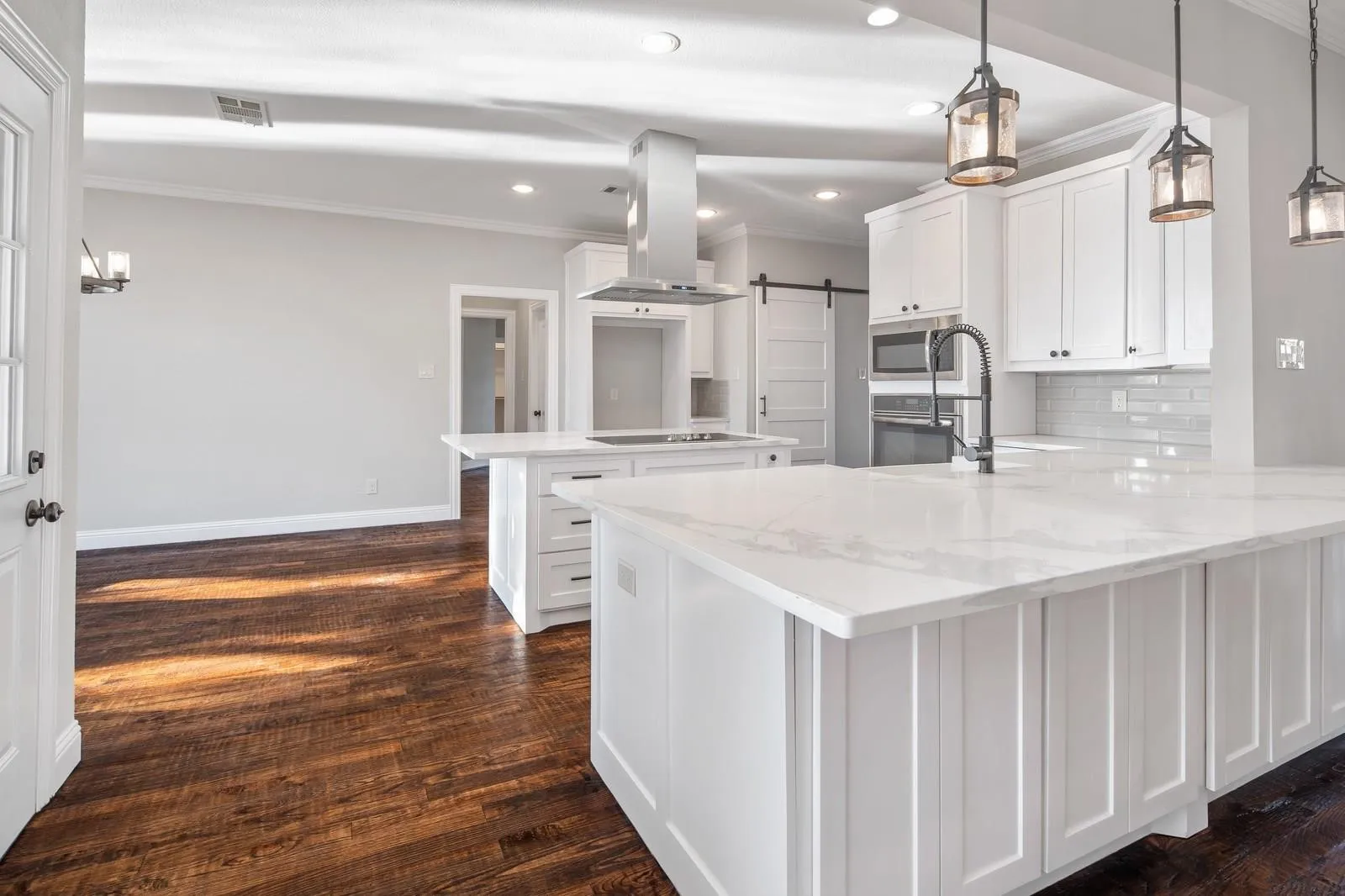 Kitchen with a peninsula, ornamental molding, a barn door, white cabinets, and light stone countertops