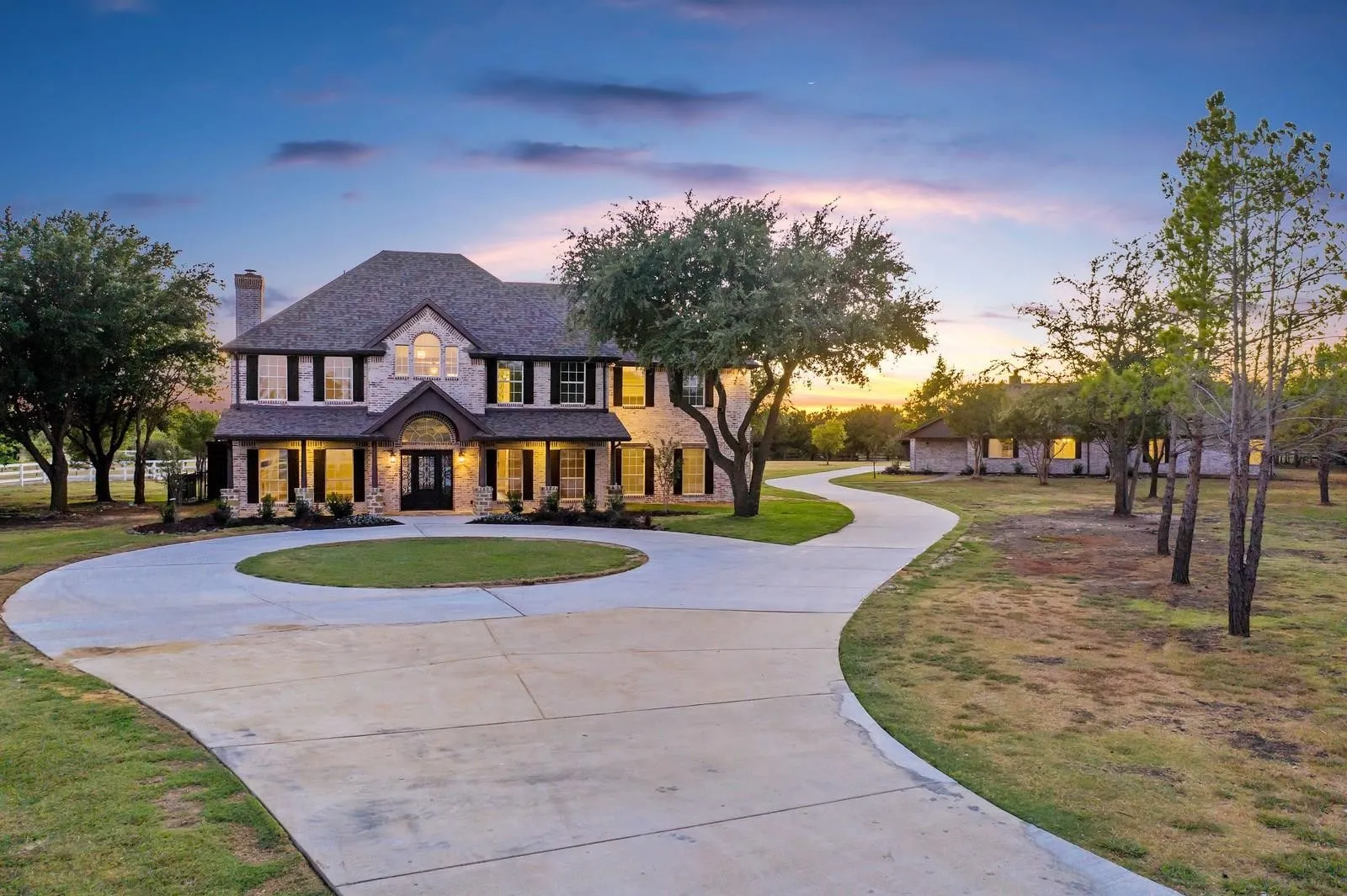 View of front of house featuring curved driveway, stone siding, a chimney, a porch, and brick siding