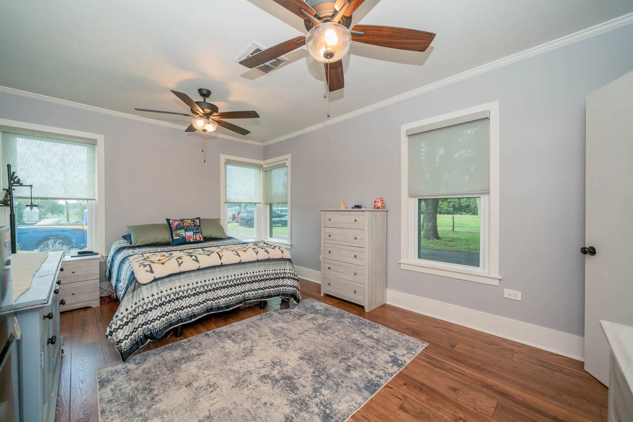 Bedroom with crown molding, dark wood-type flooring, and ceiling fan