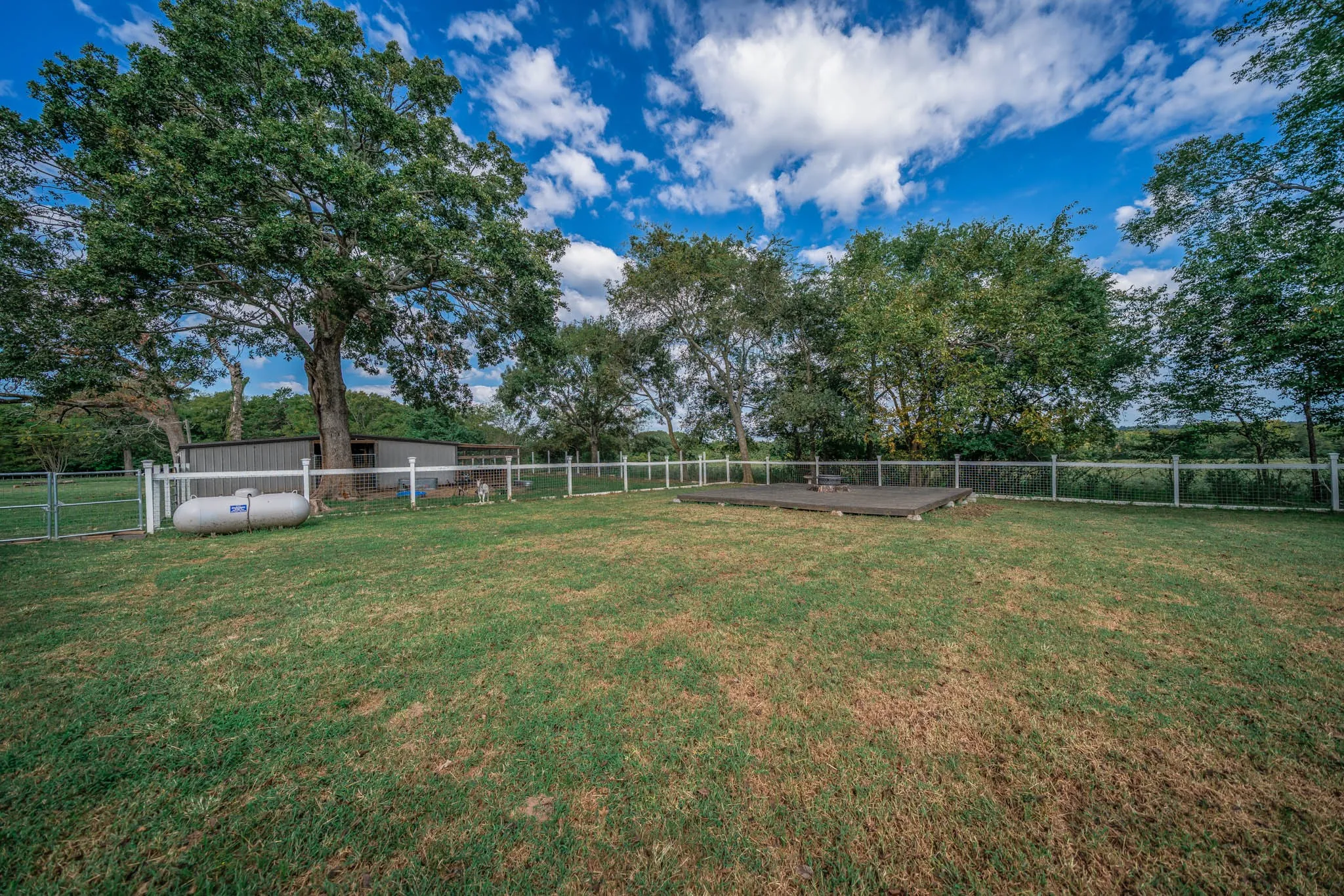 Fenced backyard featuring view of scattered trees