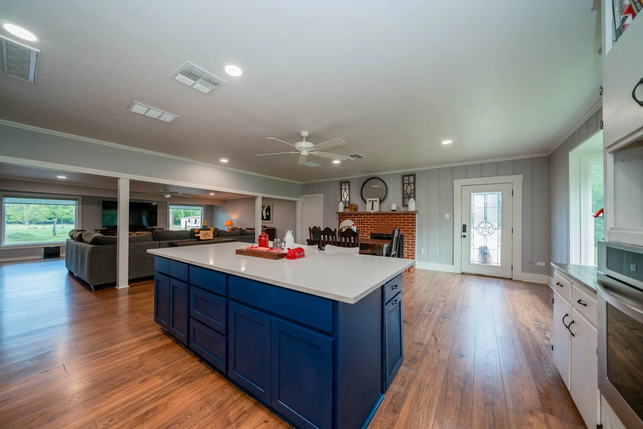 Kitchen featuring blue cabinets, open floor plan, a brick fireplace, crown molding, and stainless steel oven
