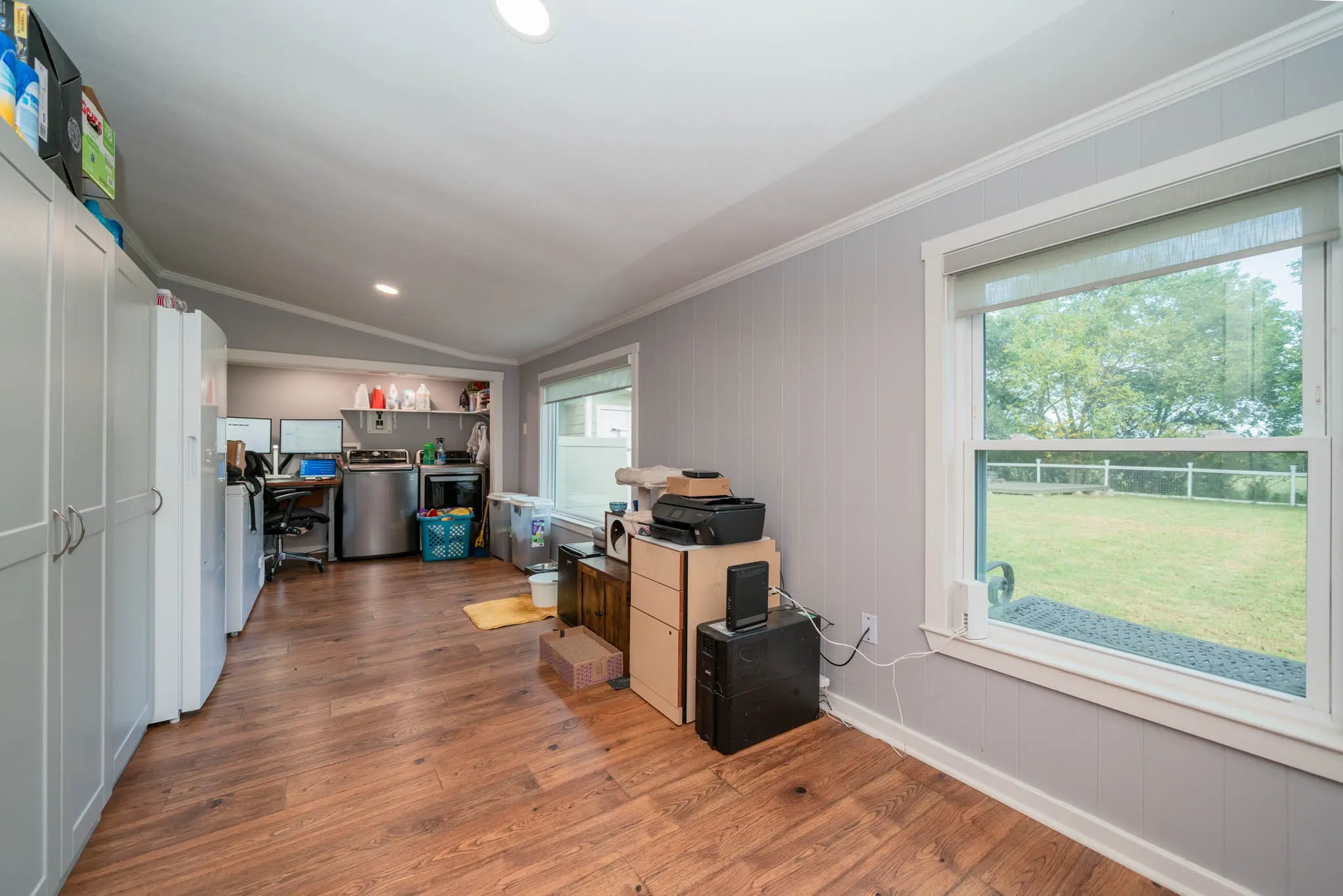 Kitchen with vaulted ceiling, a desk, wood finished floors, washer / dryer, and ornamental molding