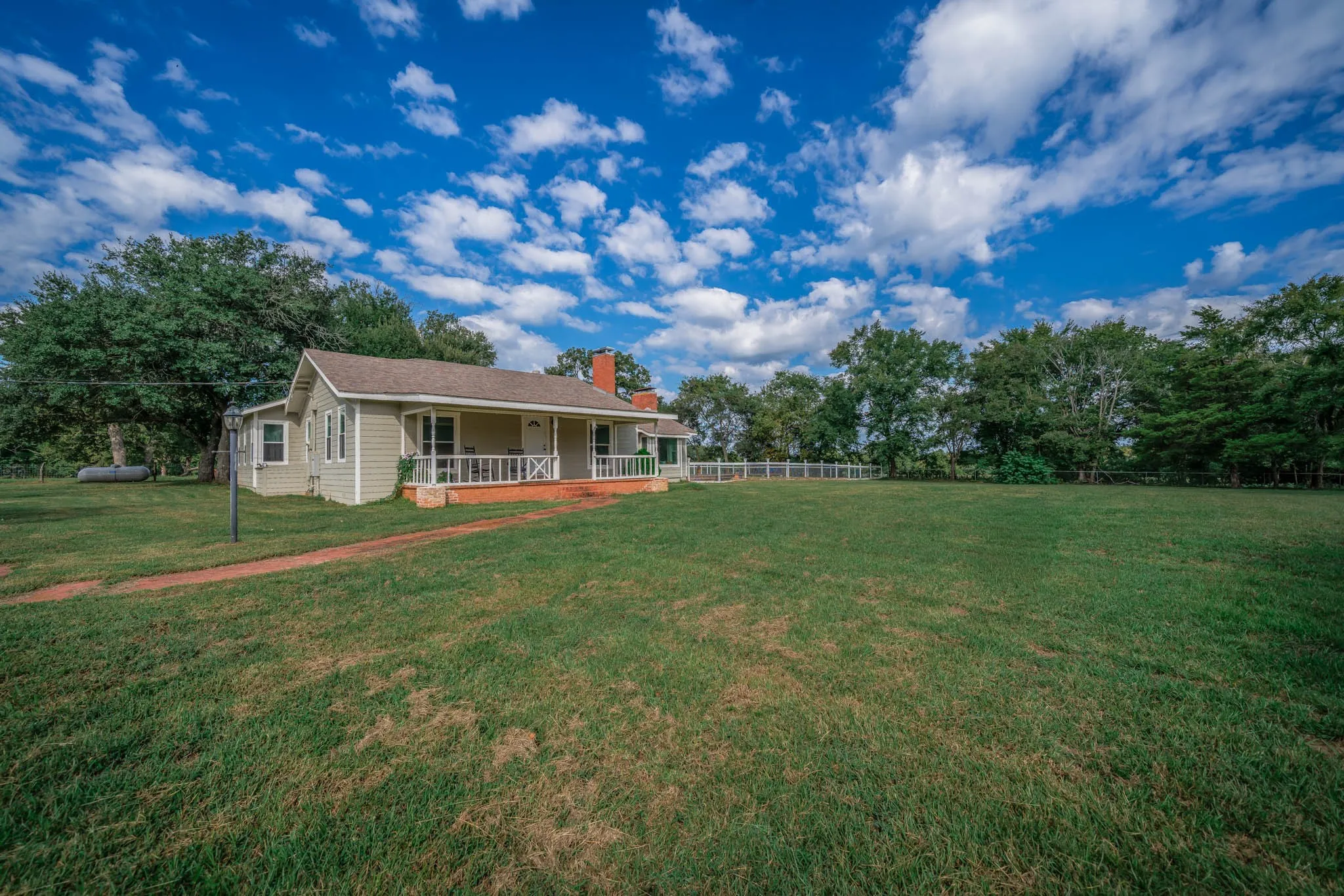 View of yard featuring a porch and view of wooded area