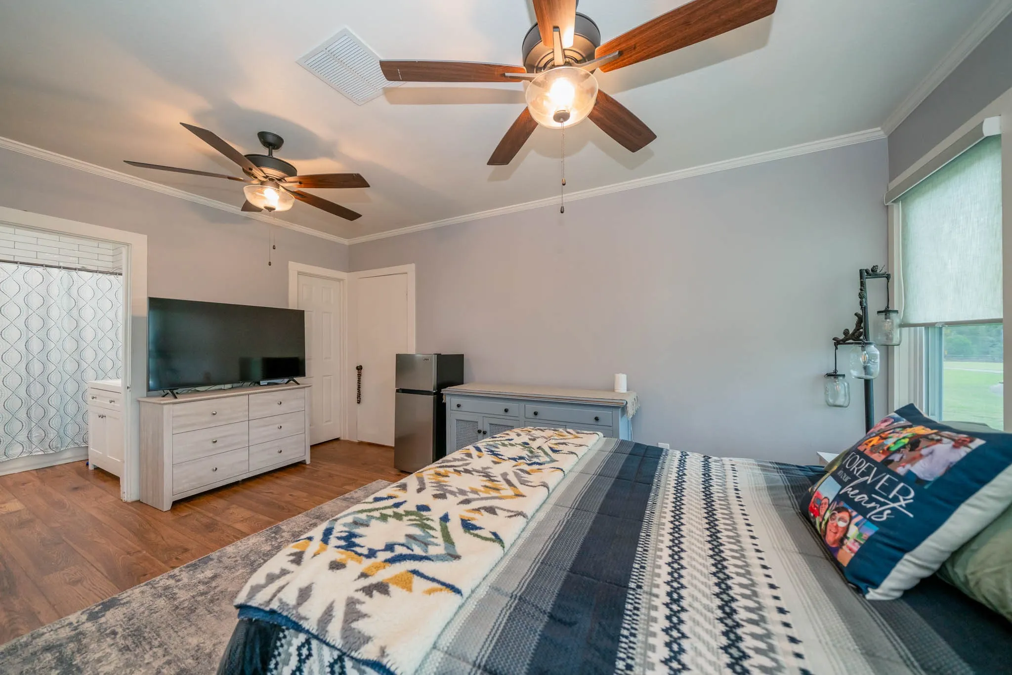Bedroom featuring crown molding, freestanding refrigerator, wood finished floors, and a ceiling fan