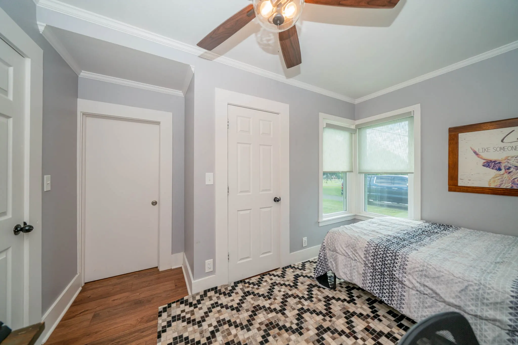 Bedroom featuring dark wood finished floors, ornamental molding, and a ceiling fan