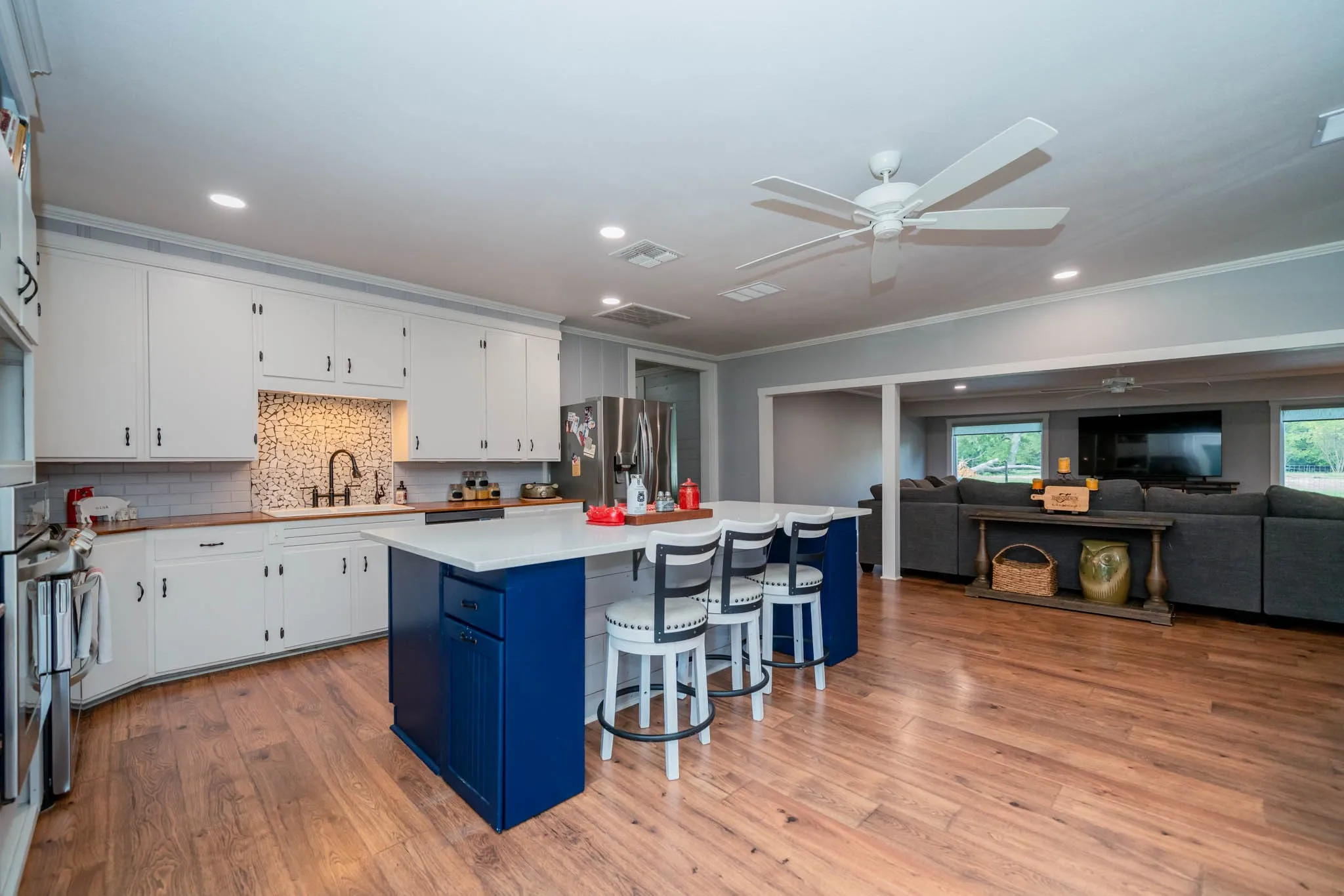 Kitchen featuring tasteful backsplash, ornamental molding, a center island, white cabinetry, and light wood-style flooring