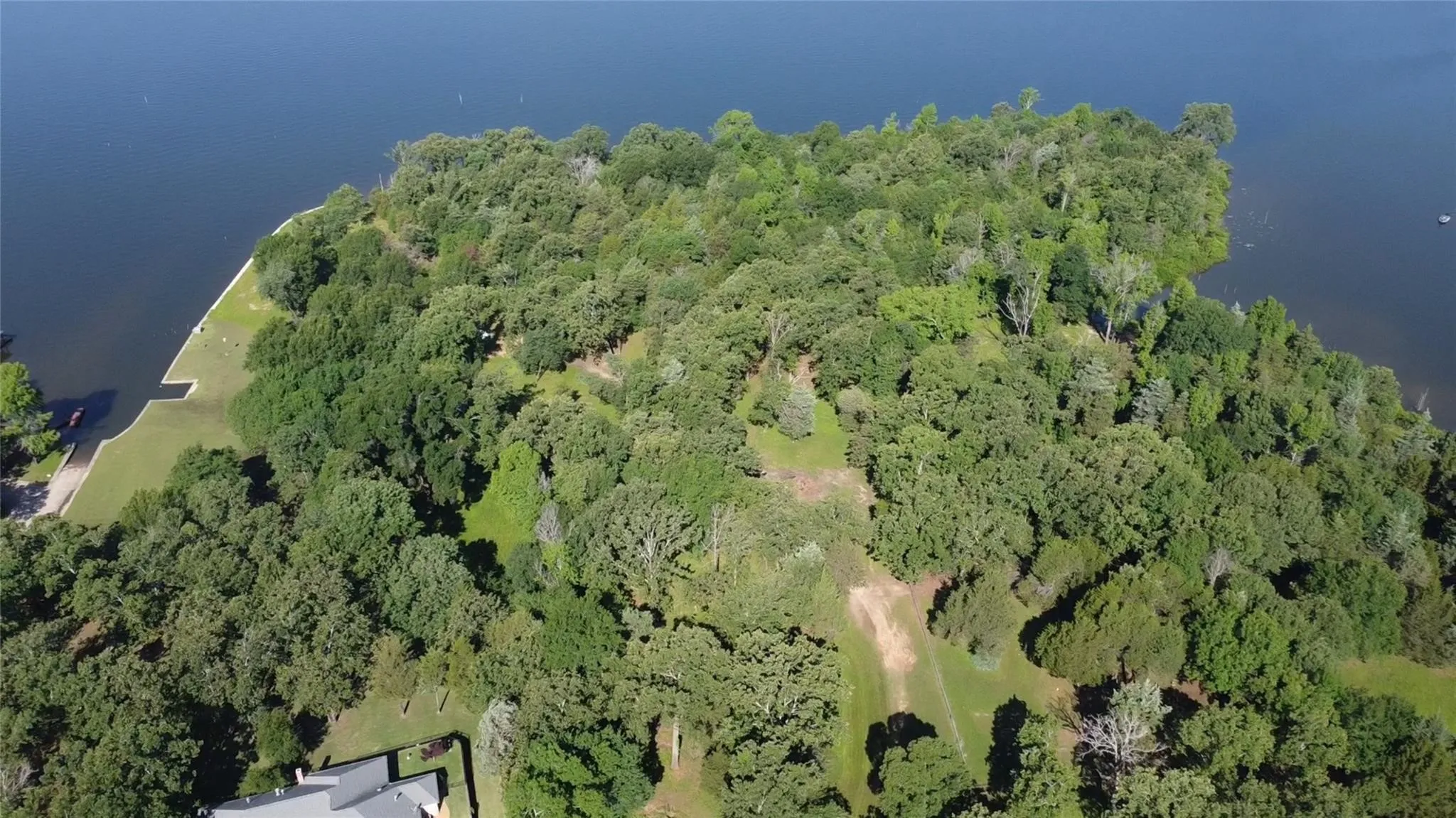 Aerial overview of property's location featuring a forest and a nearby body of water