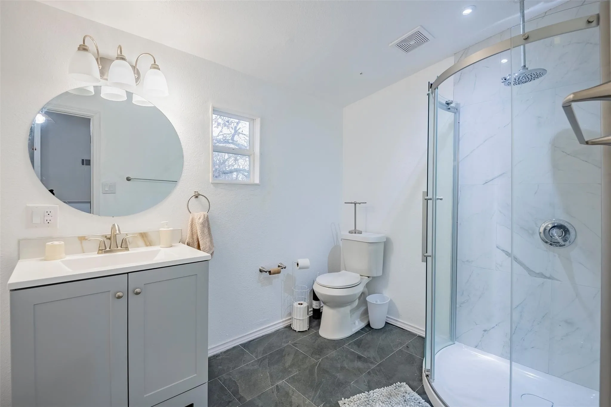 Bathroom with a marble finish shower and vanity
