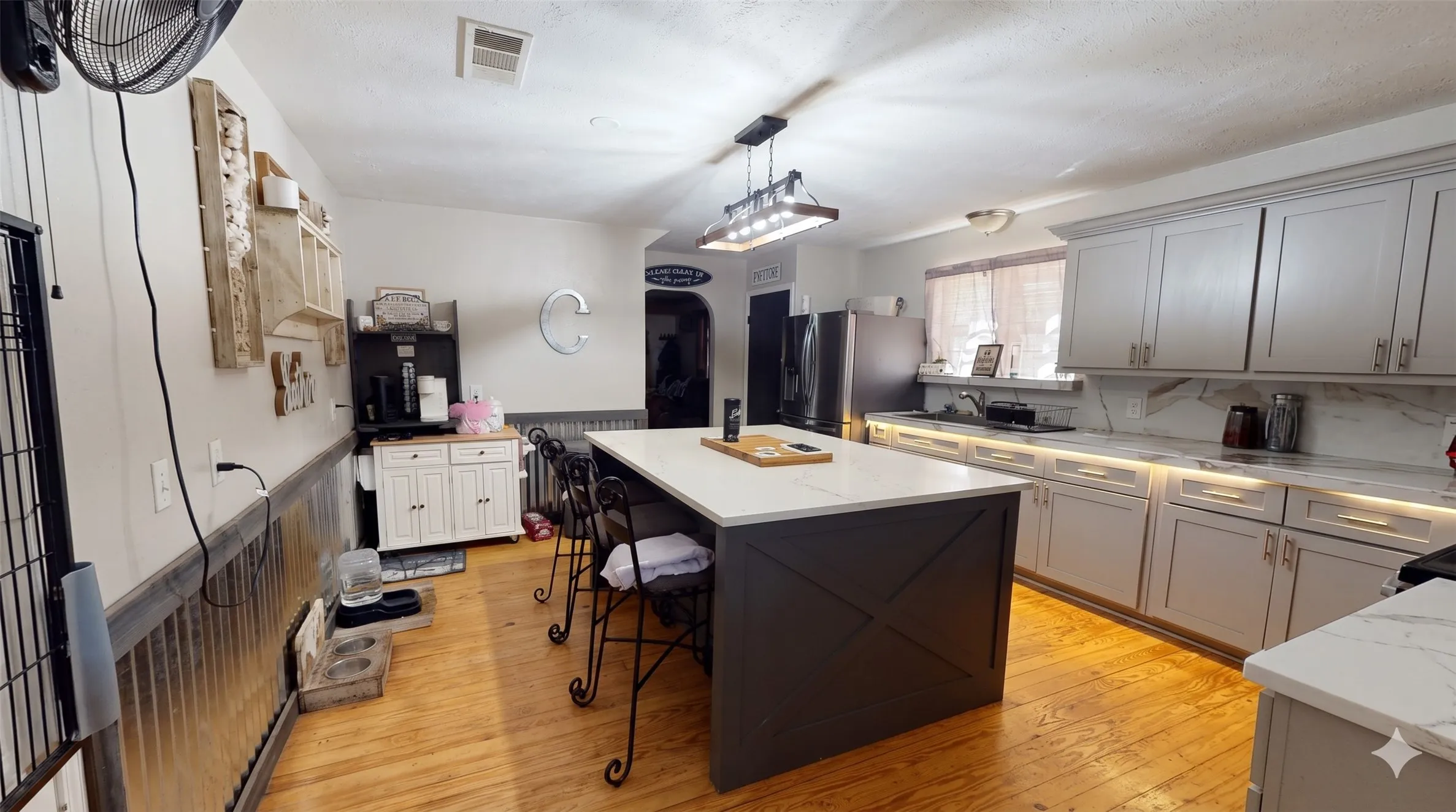Kitchen with stainless steel fridge with ice dispenser, light wood-style flooring, a textured ceiling, light stone countertops, and decorative light fixtures