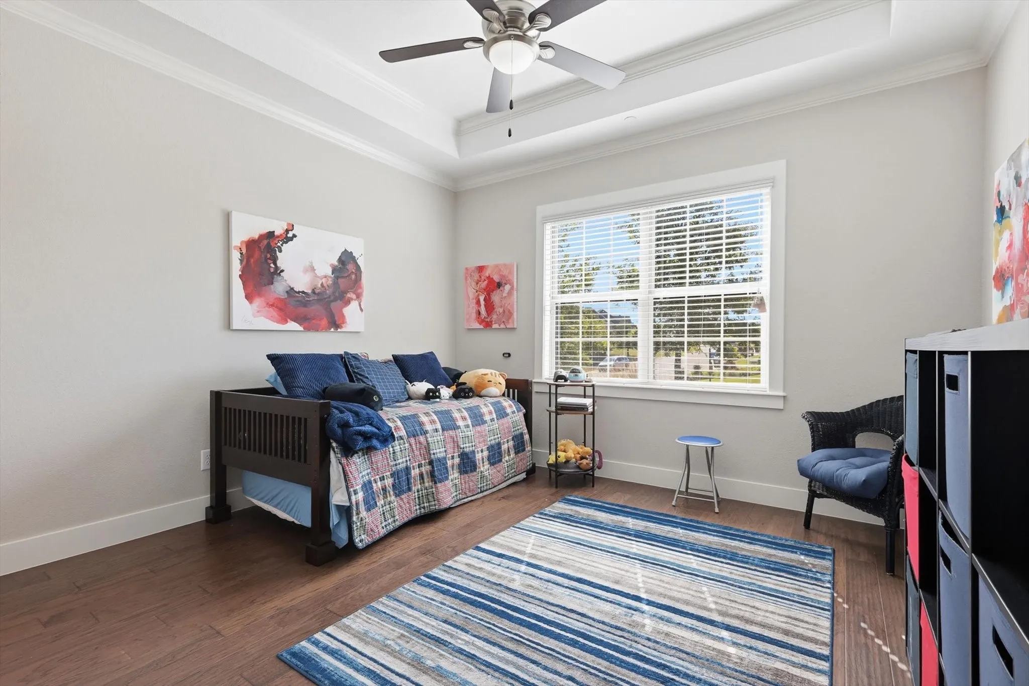 Secondary bedroom at the front of the house with a tray ceiling and ceiling fan.