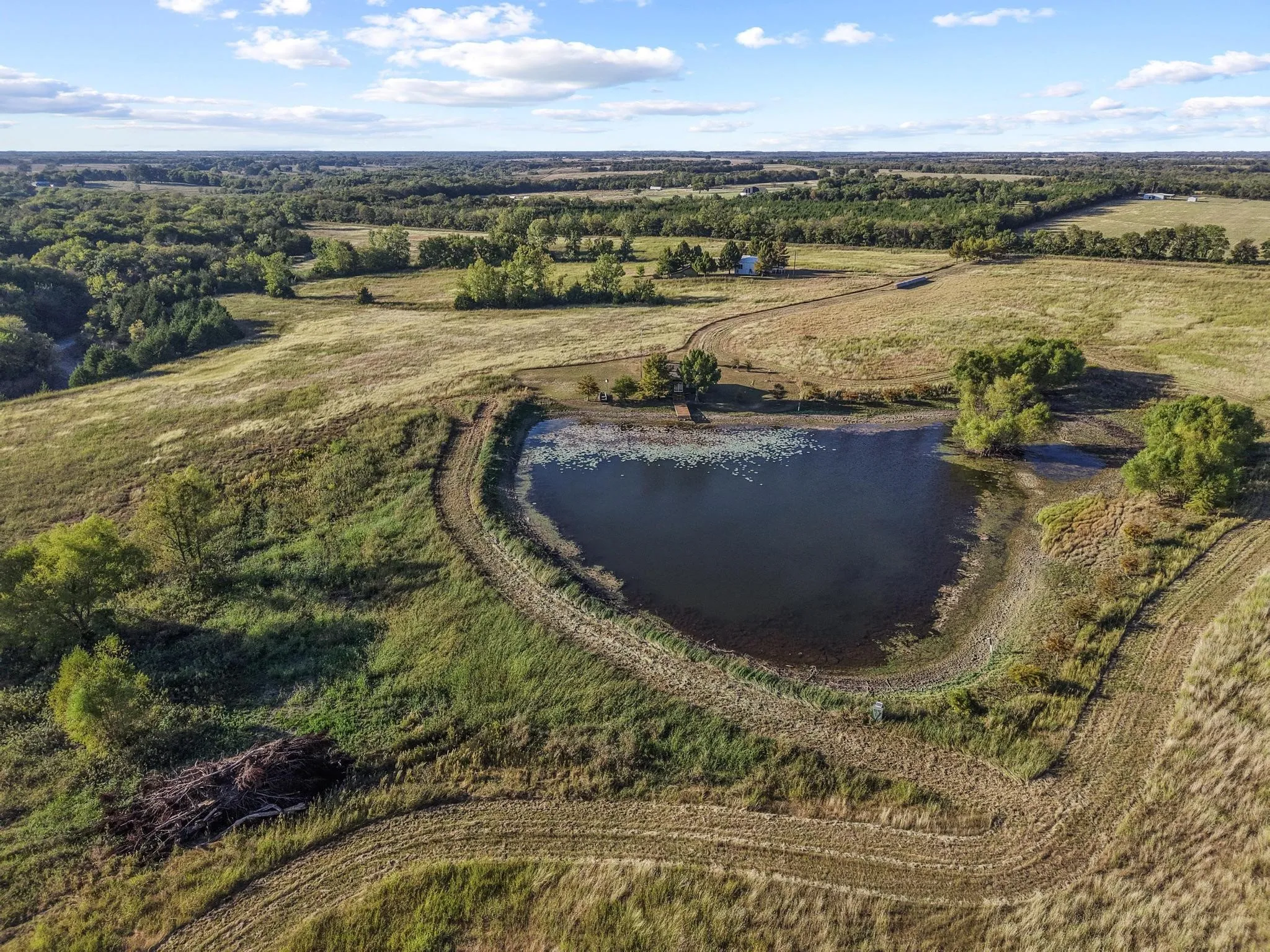 Aerial view of cabin on pond with shop and outbuilding in the distance