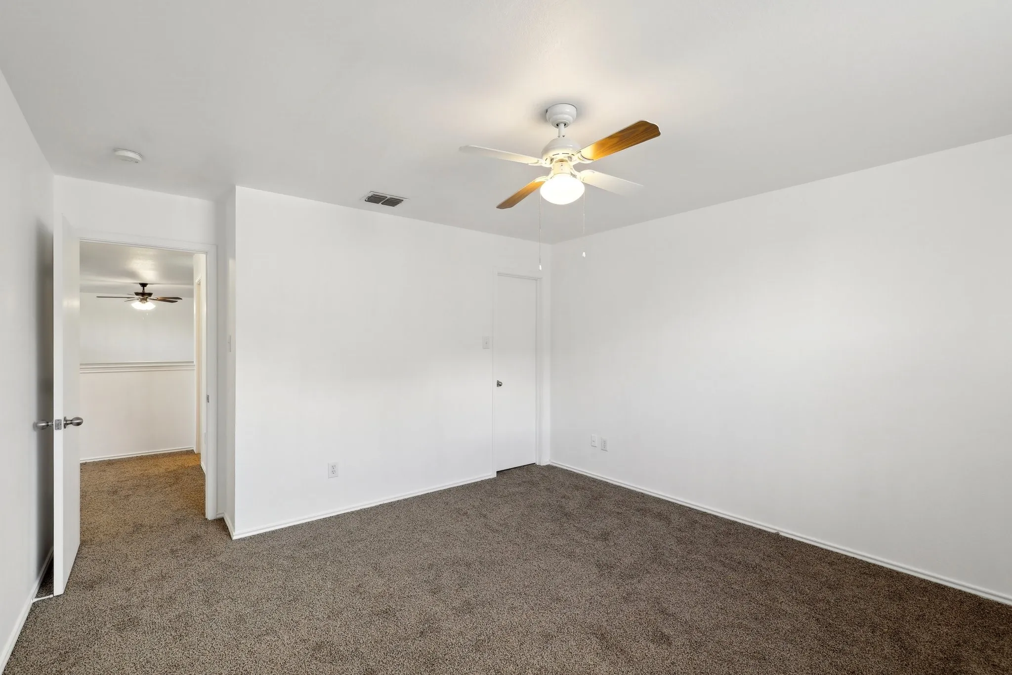 Unfurnished bedroom with dark colored carpet and ceiling fan