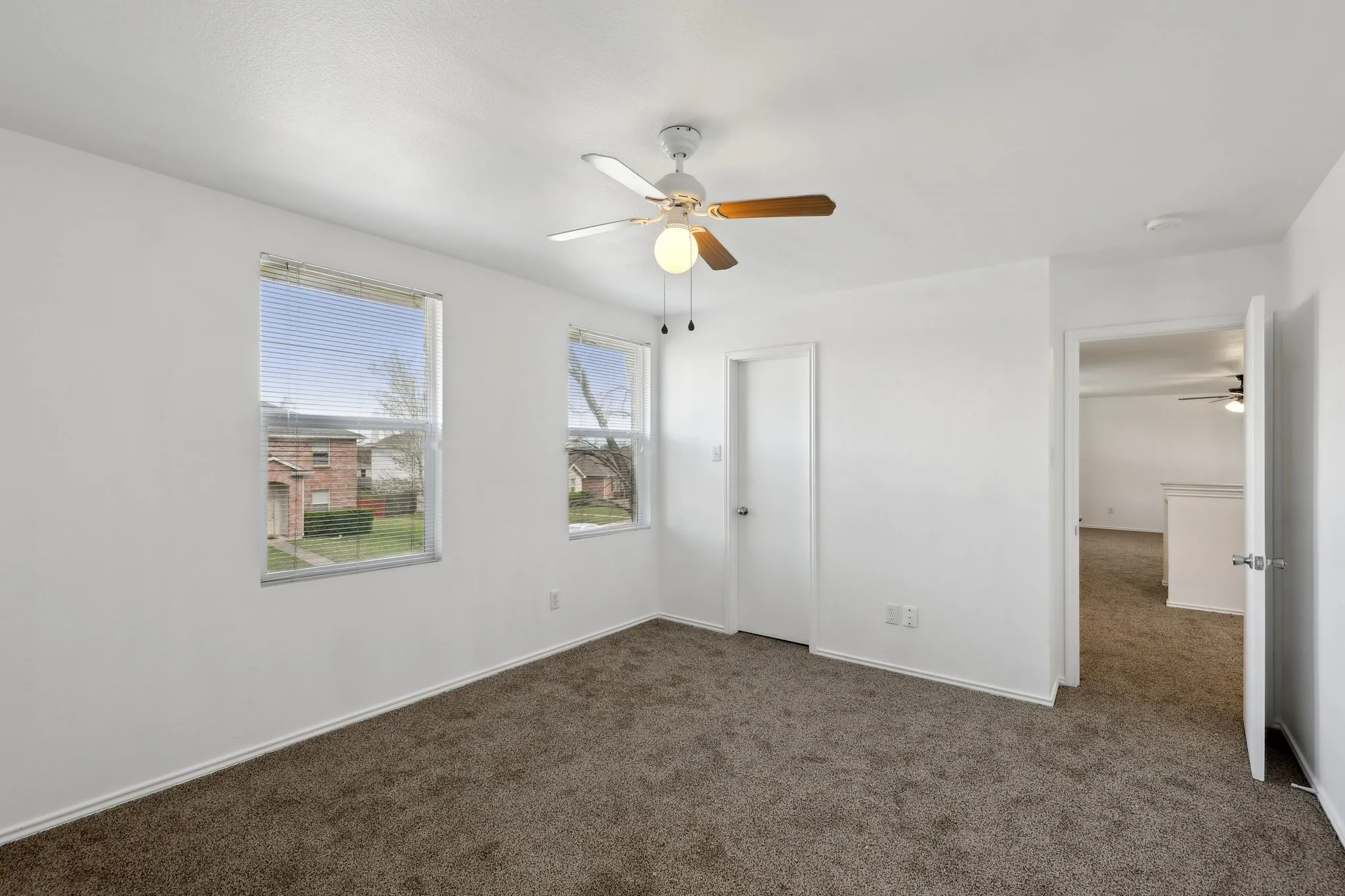 Unfurnished bedroom with dark carpet and ceiling fan