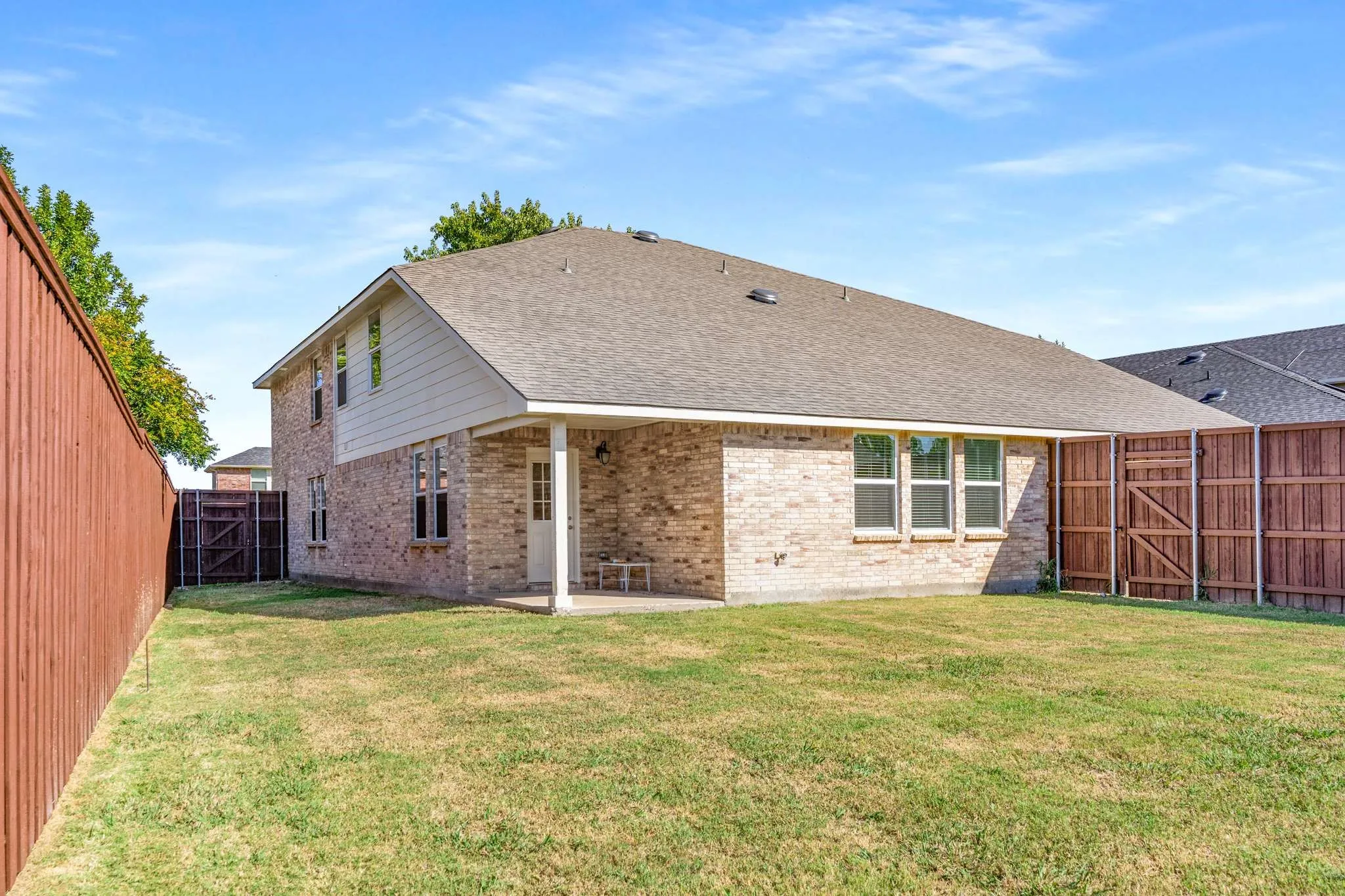 Back of property with a gate, a patio, roof with shingles, and a fenced backyard