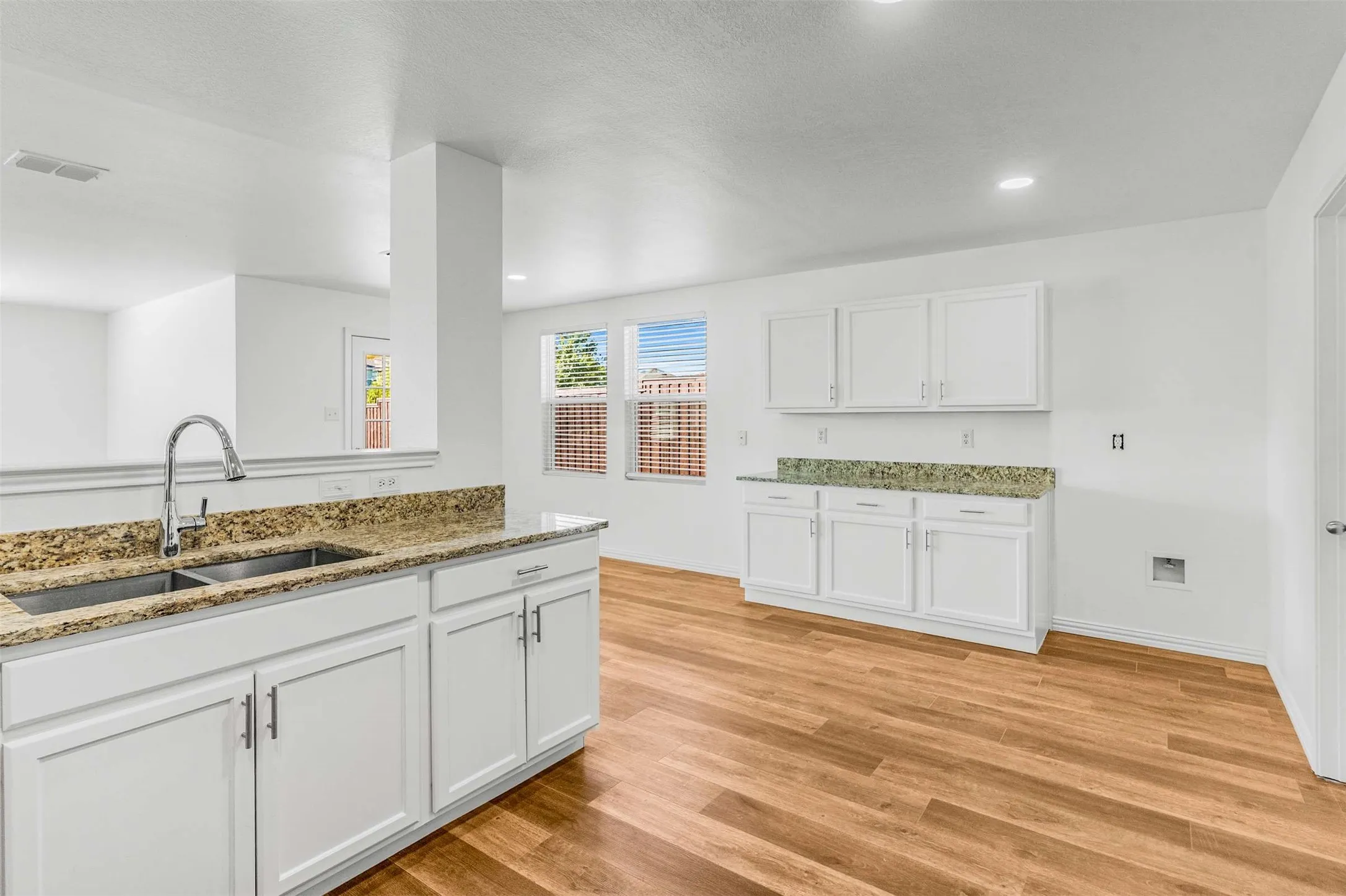 Kitchen with white cabinetry, light stone counters, light wood-style flooring, and recessed lighting
