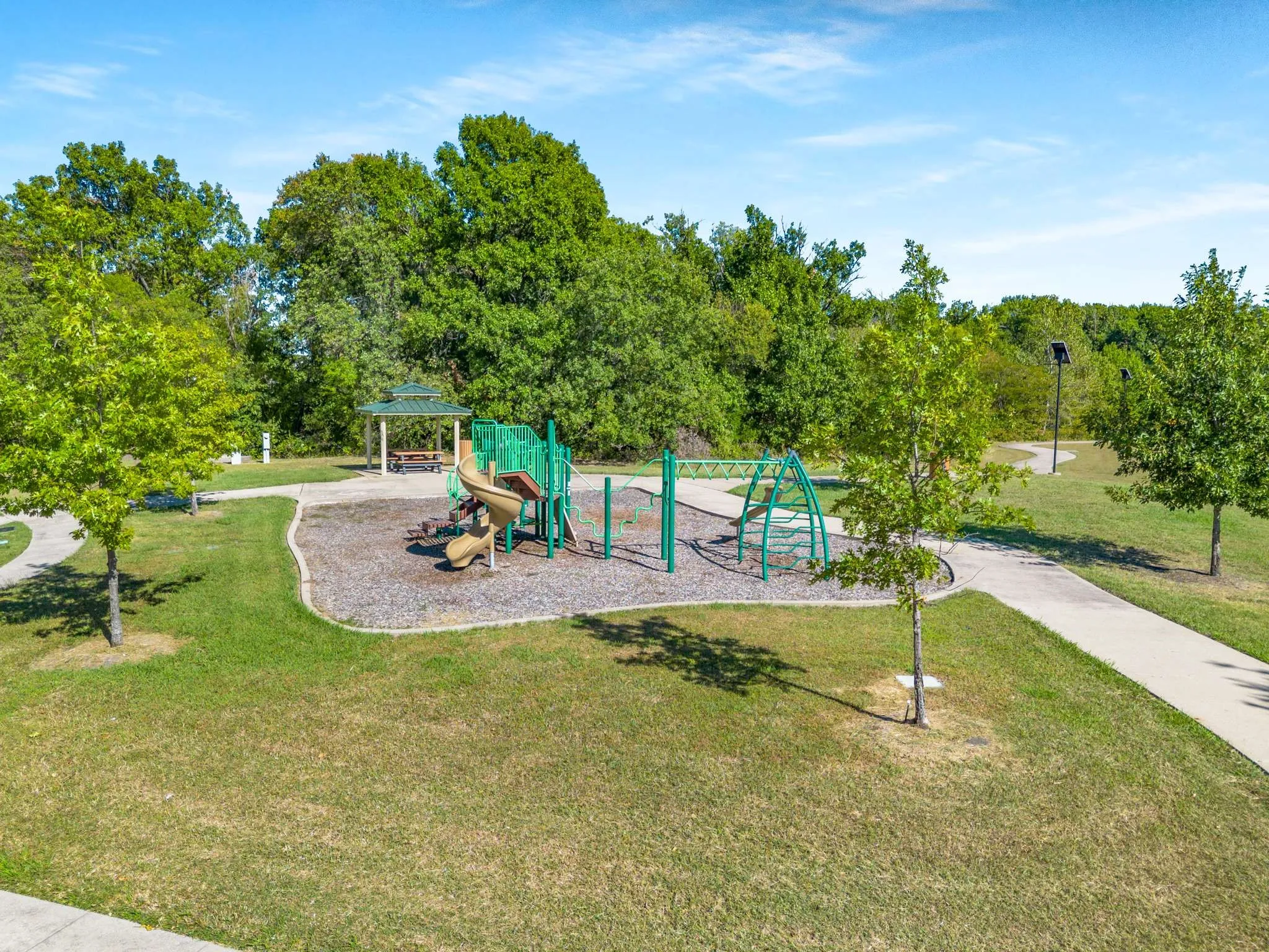 Community jungle gym featuring a yard, a gazebo, and view of wooded area