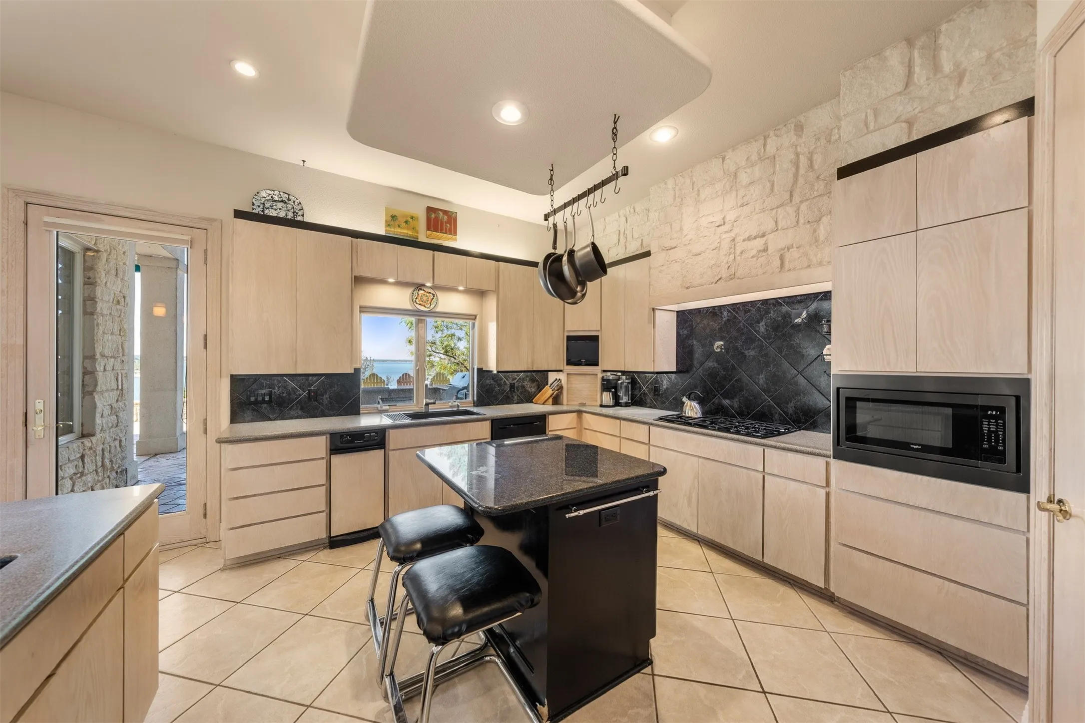 Kitchen with light brown cabinetry, light tile patterned floors, backsplash, and recessed lighting