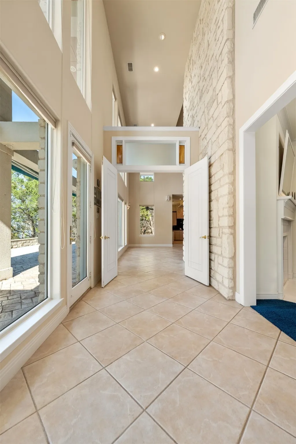 Corridor with a towering ceiling, light tile patterned floors, and recessed lighting