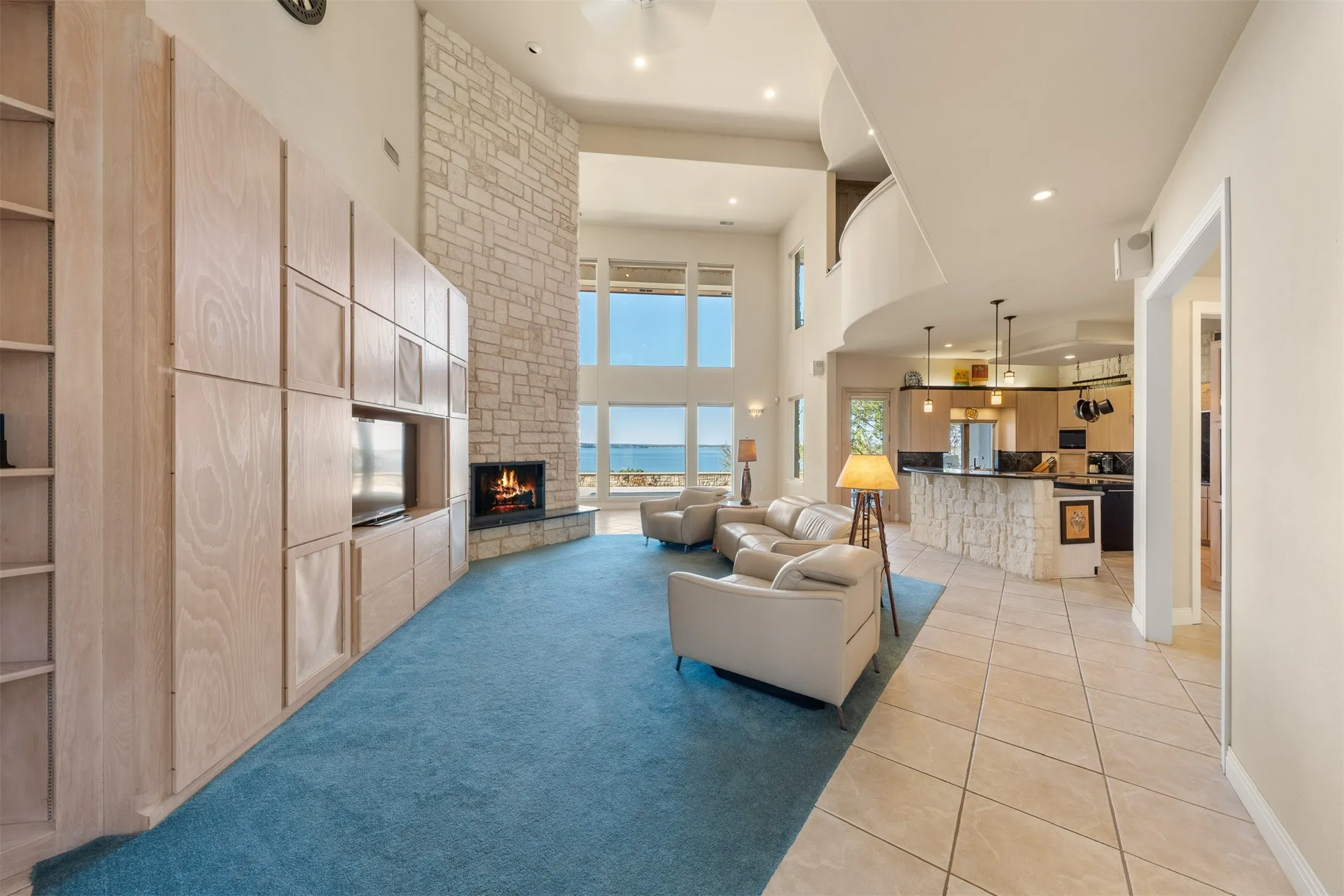 Living area with light tile patterned floors, a high ceiling, a fireplace, recessed lighting, and light carpet