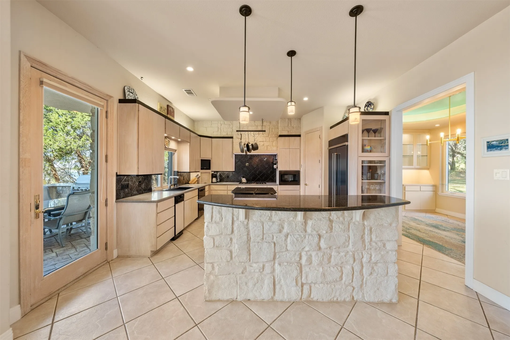 Kitchen with light brown cabinetry, tasteful backsplash, dark stone countertops, light tile patterned floors, and recessed lighting