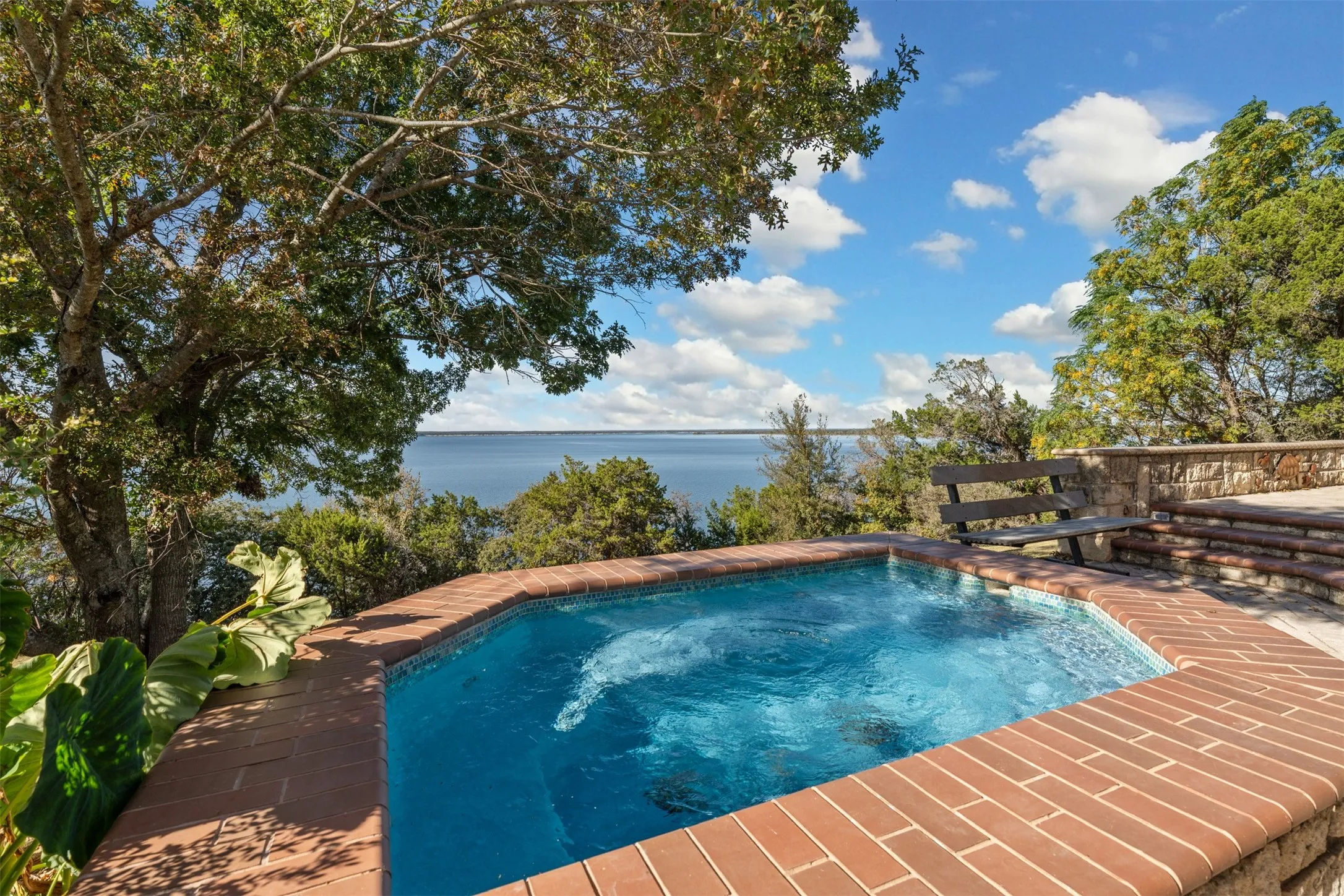 View of swimming pool with a water view and a hot tub