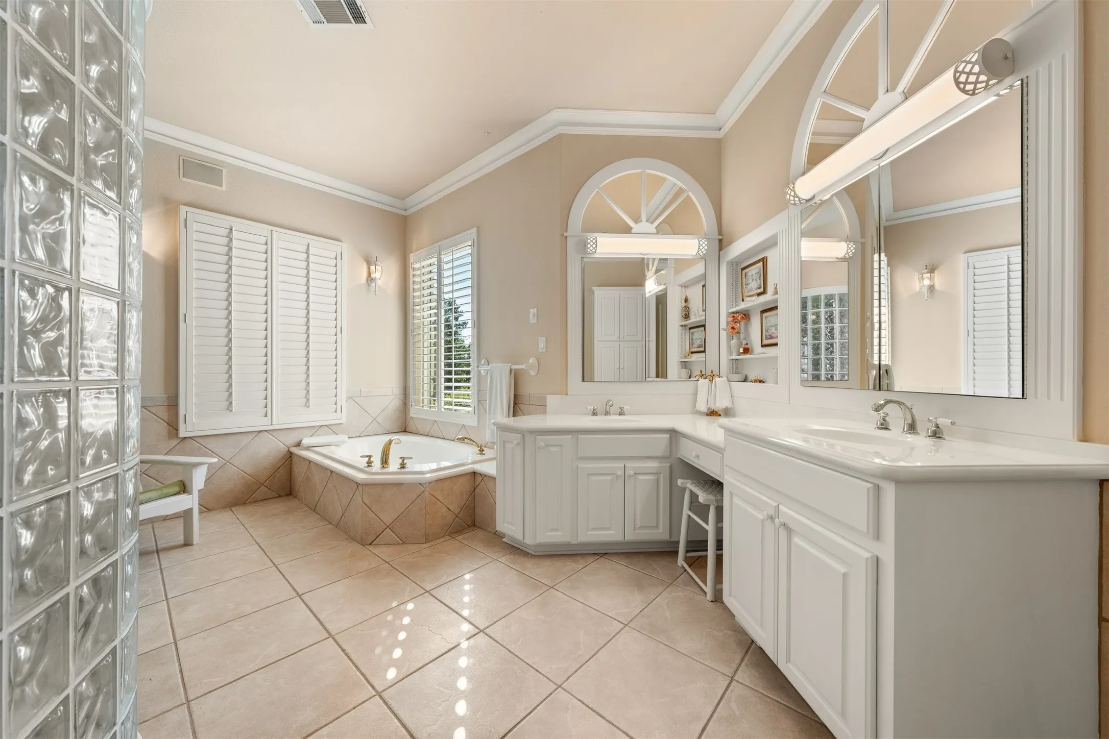 Bathroom with ornamental molding, a bath, light tile patterned floors, and double vanity