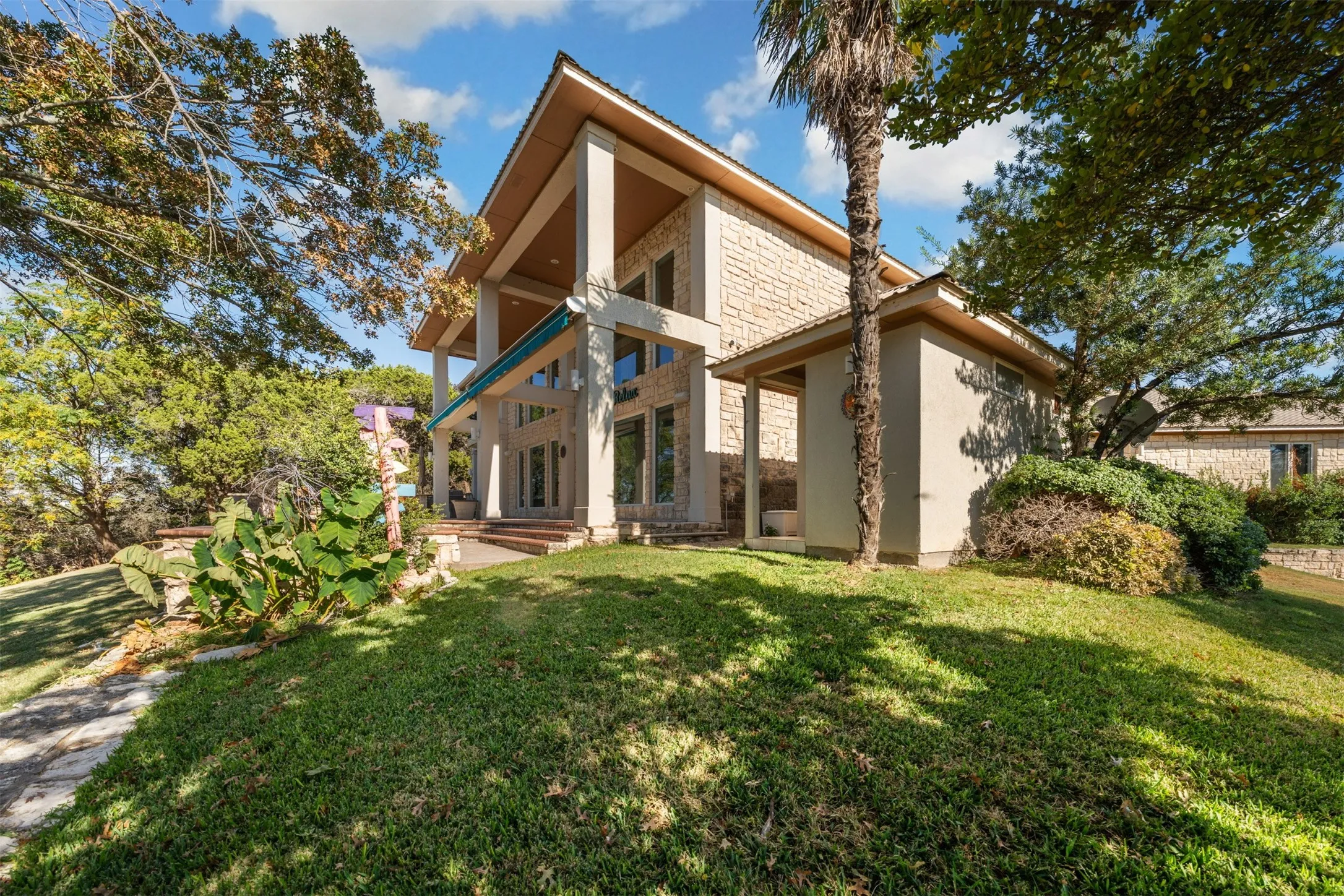Back of property featuring stone siding, a yard, a patio area, and stucco siding