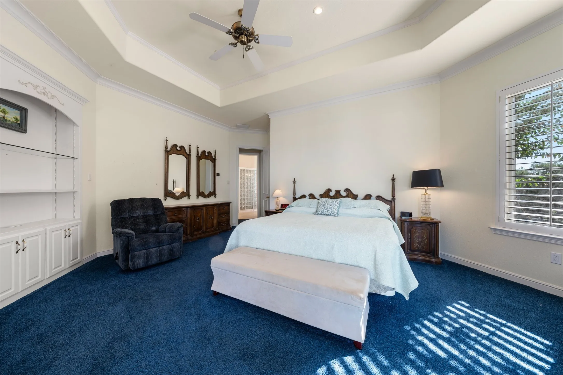 Bedroom featuring a tray ceiling, ornamental molding, carpet, and a ceiling fan