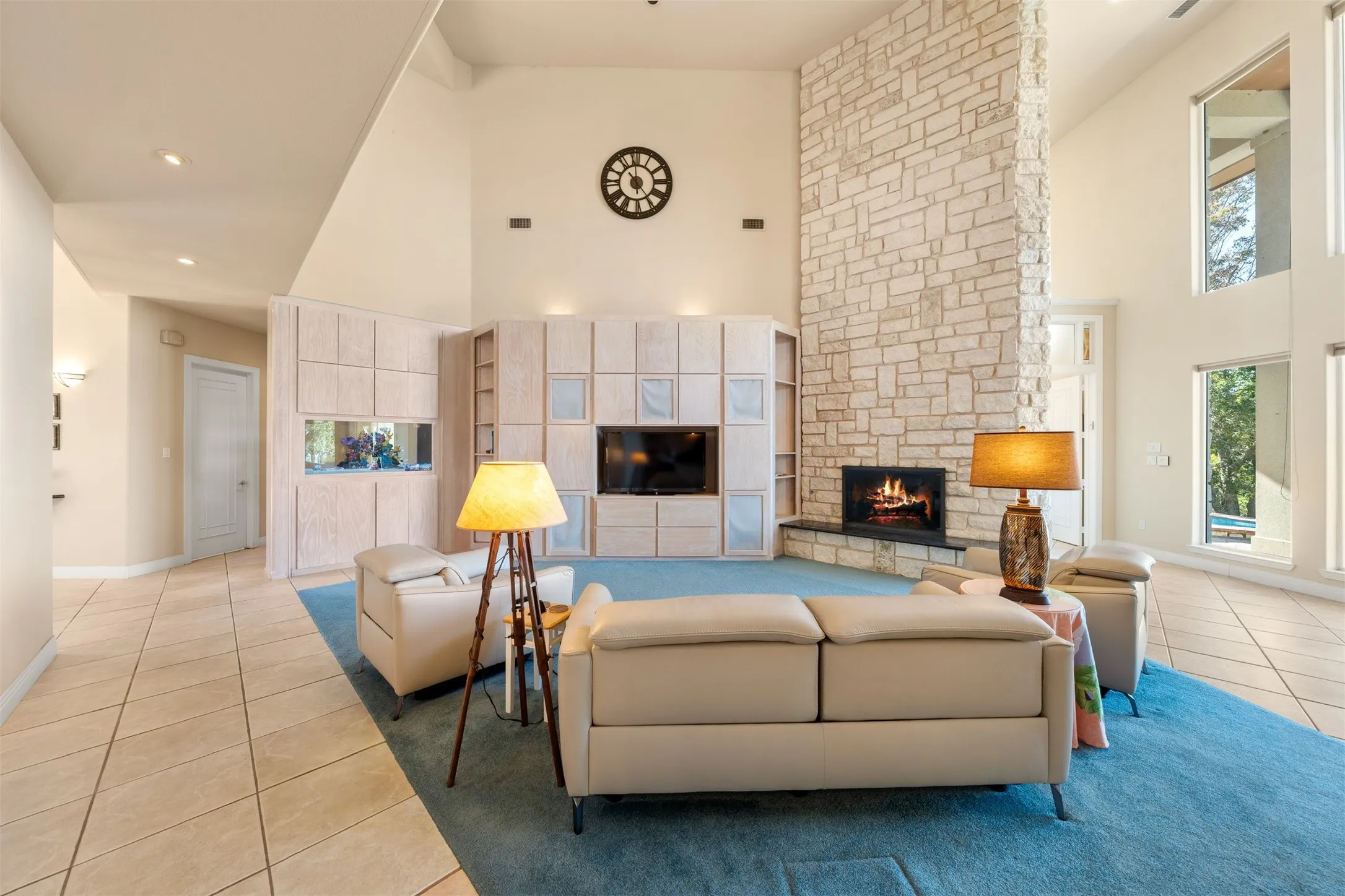 Living room with high vaulted ceiling, light tile patterned floors, a fireplace, light carpet, and recessed lighting