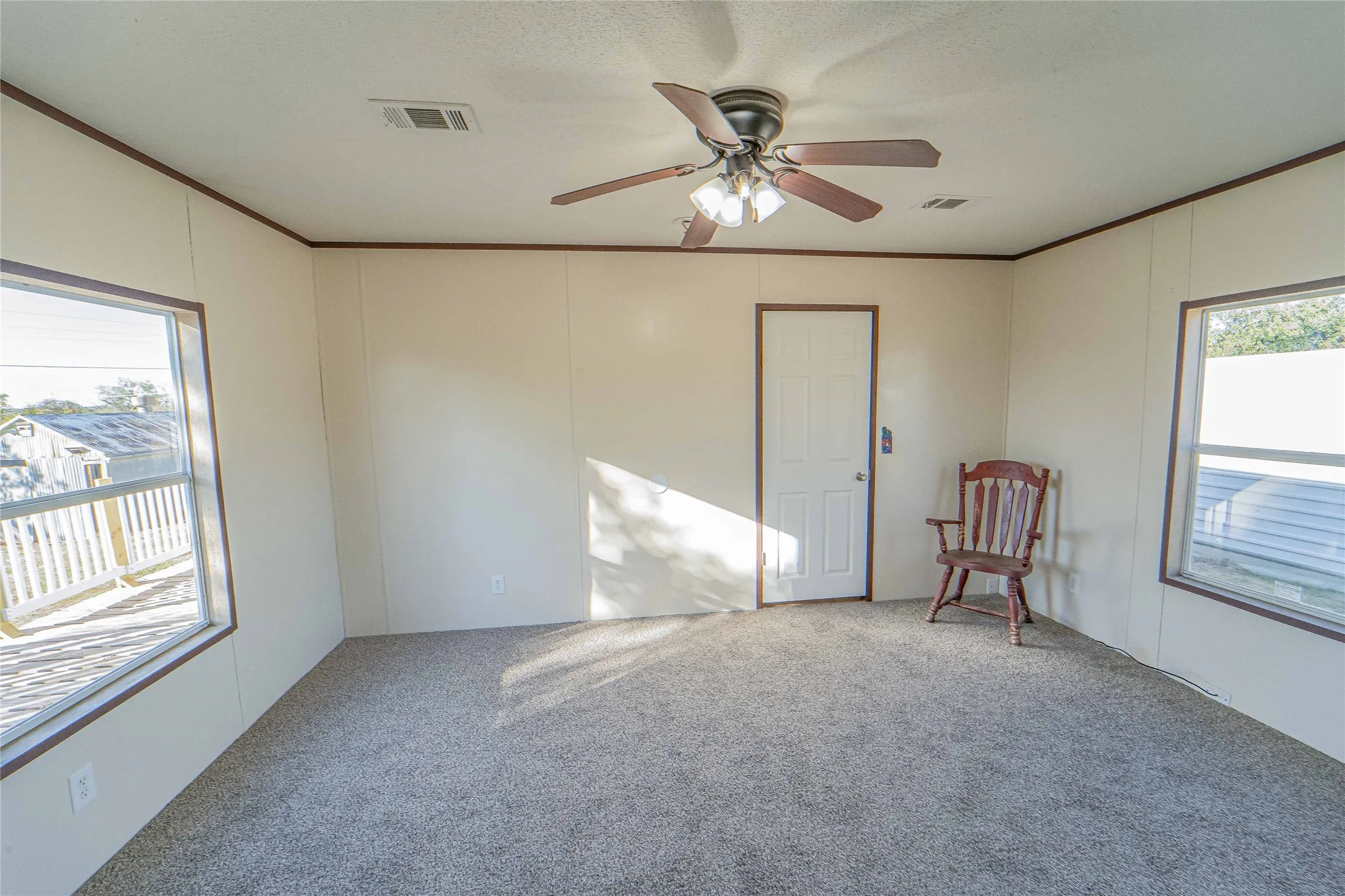 Empty room with healthy amount of natural light, crown molding, carpet flooring, a ceiling fan, and a decorative wall