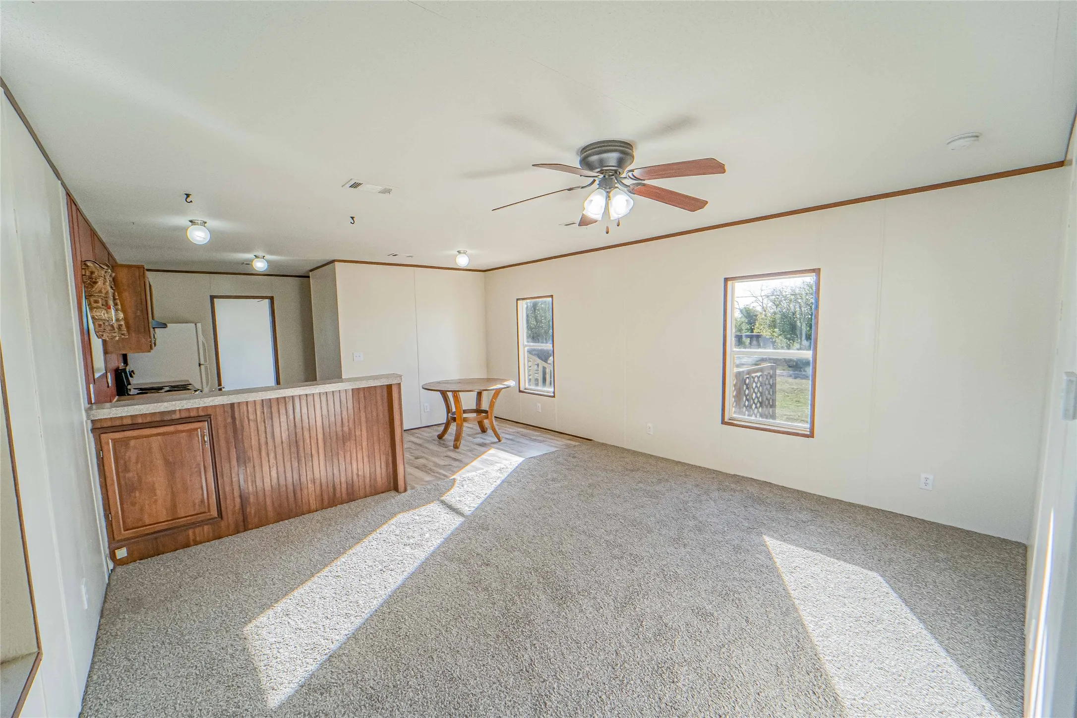 Kitchen featuring brown cabinetry, a peninsula, light countertops, light colored carpet, and crown molding