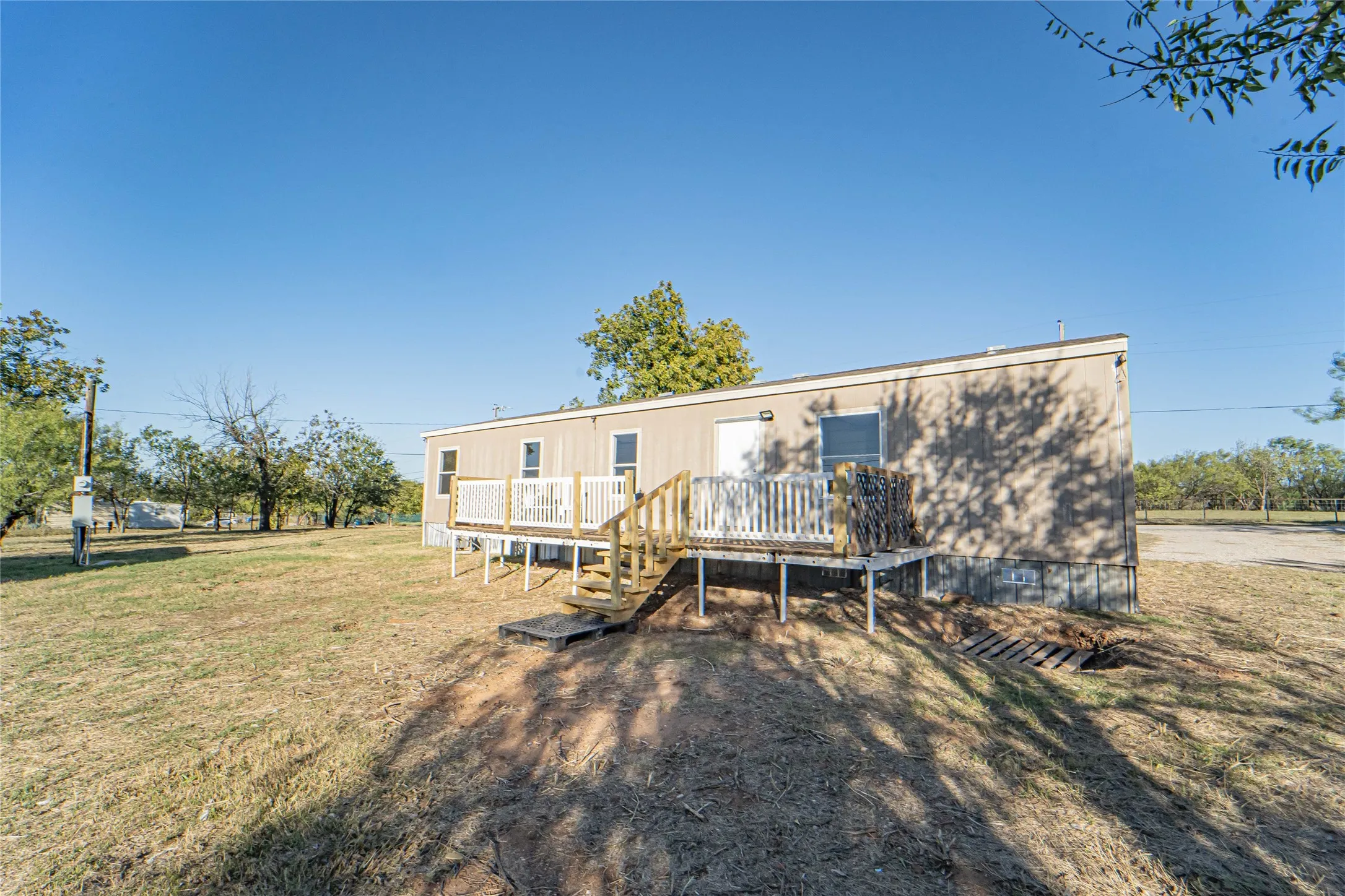 Back of house with a lawn and a deck