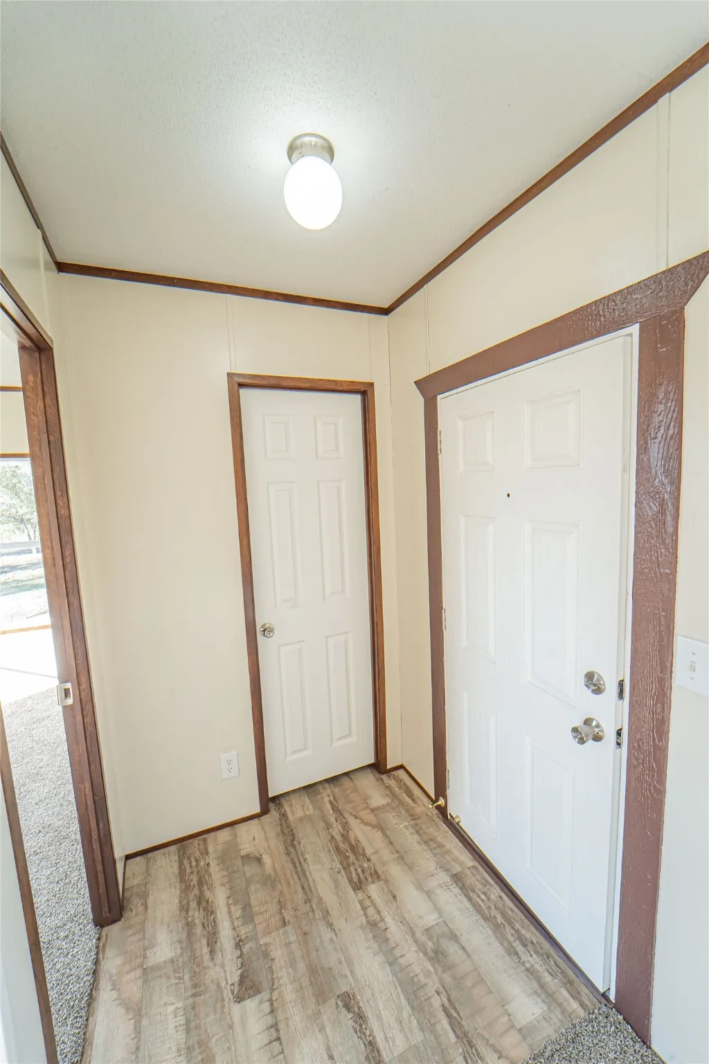 Foyer with crown molding, light wood finished floors, and a textured ceiling