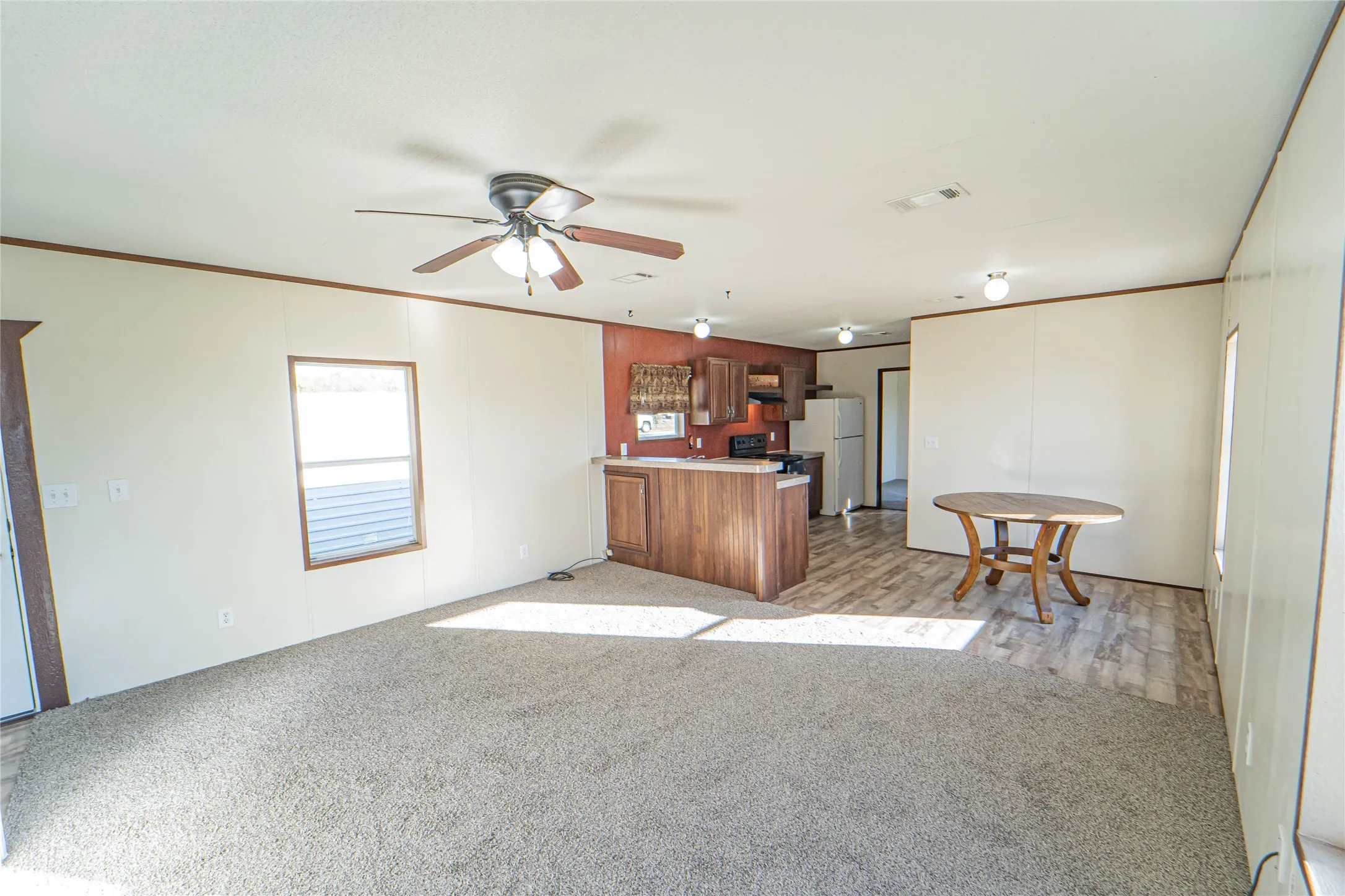 Kitchen with crown molding, light colored carpet, light countertops, a peninsula, and a ceiling fan