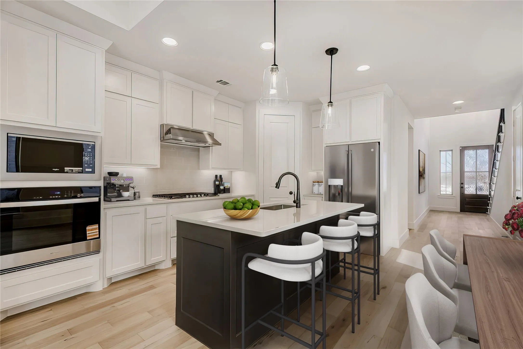VIRTUALLY STAGED PHOTO - Contemporary kitchen featuring white cabinetry, light wood-finish flooring, a dark-toned island with a light countertop, stainless steel appliances, and pendant lighting