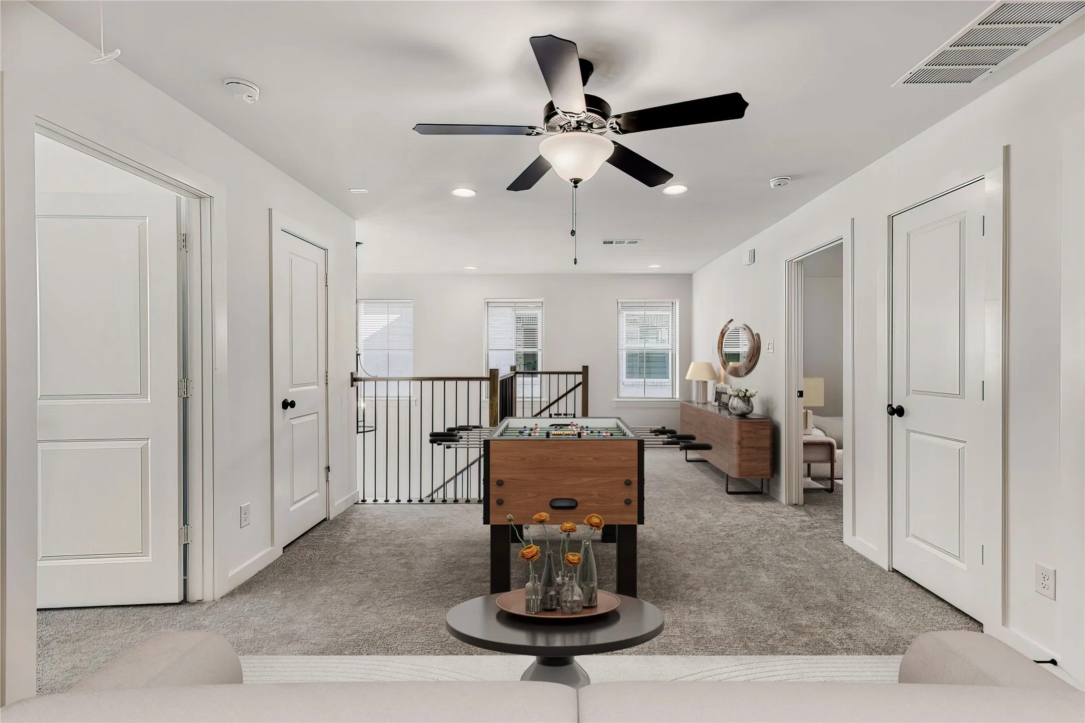 VIRTUALLY STAGED PHOTO - Open loft area featuring carpeted flooring, a ceiling fan with light, recessed lighting, and a black metal staircase railing